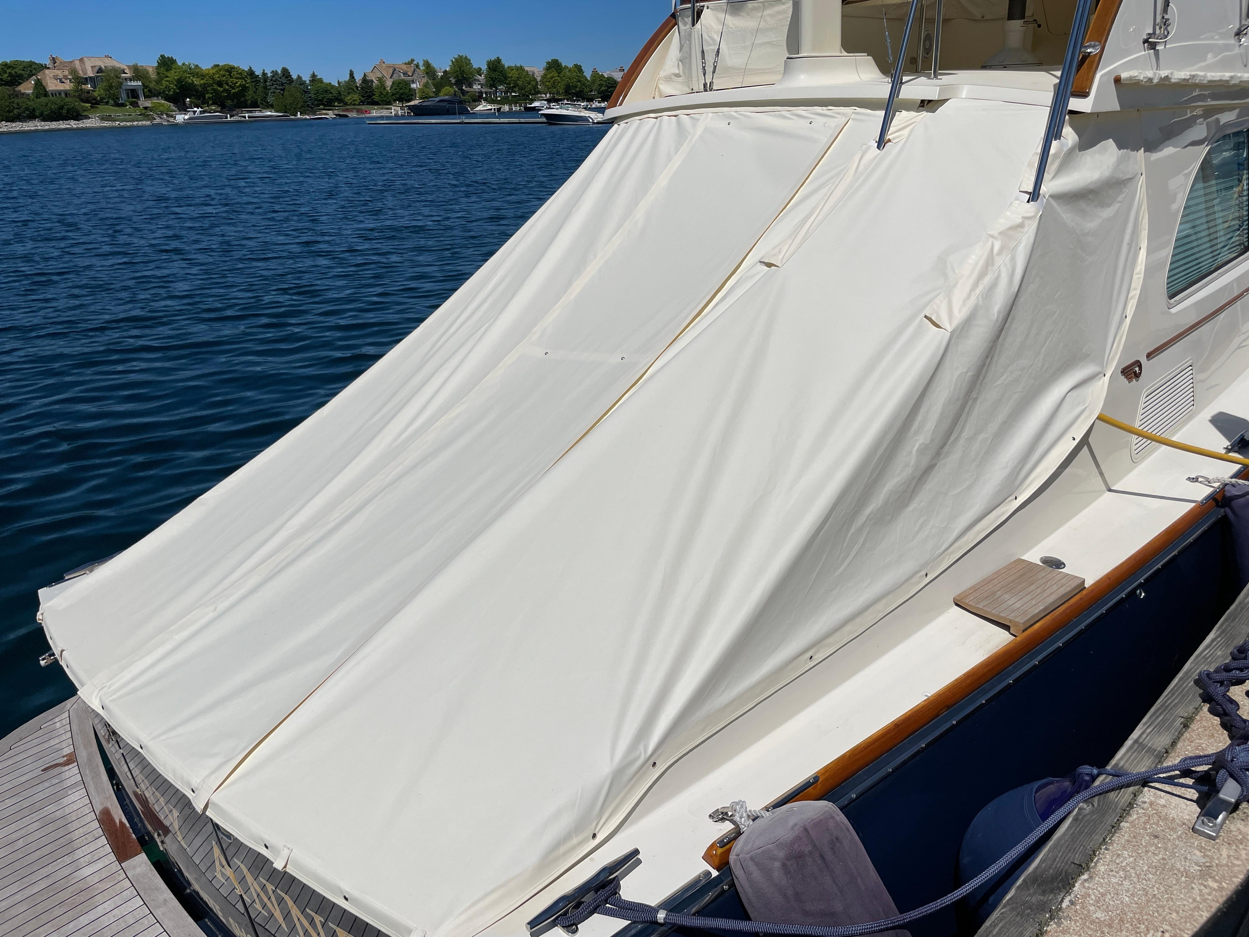 2007 Hinckley Talaria 44 Flybridge with protective cover docked by the water.
