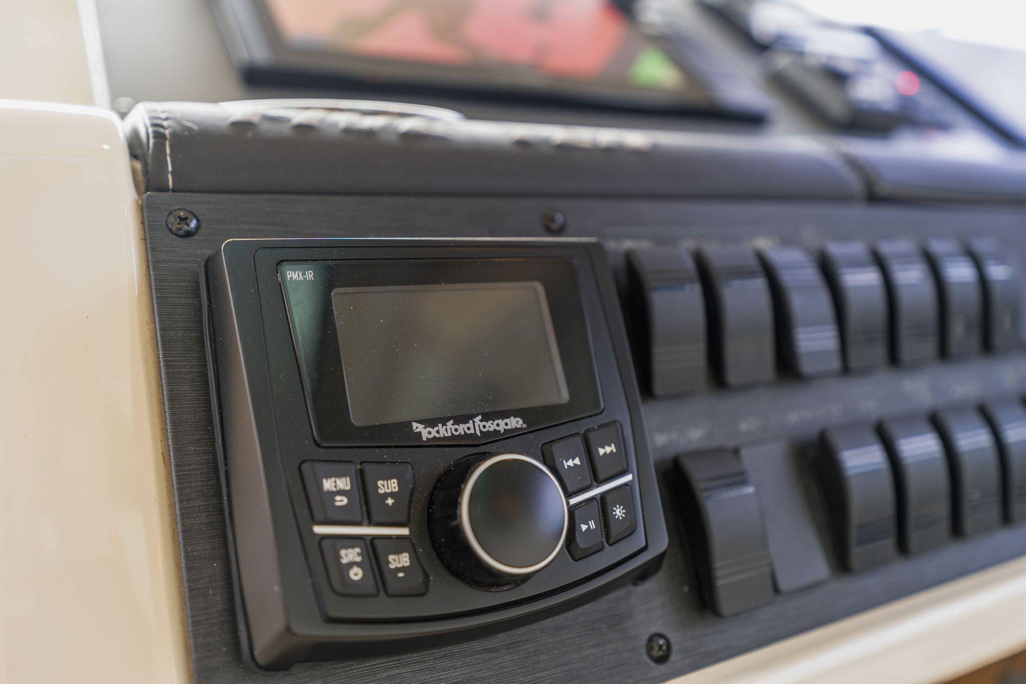 Close-up of a helm console featuring a Rockford Fosgate audio system and multiple switches.