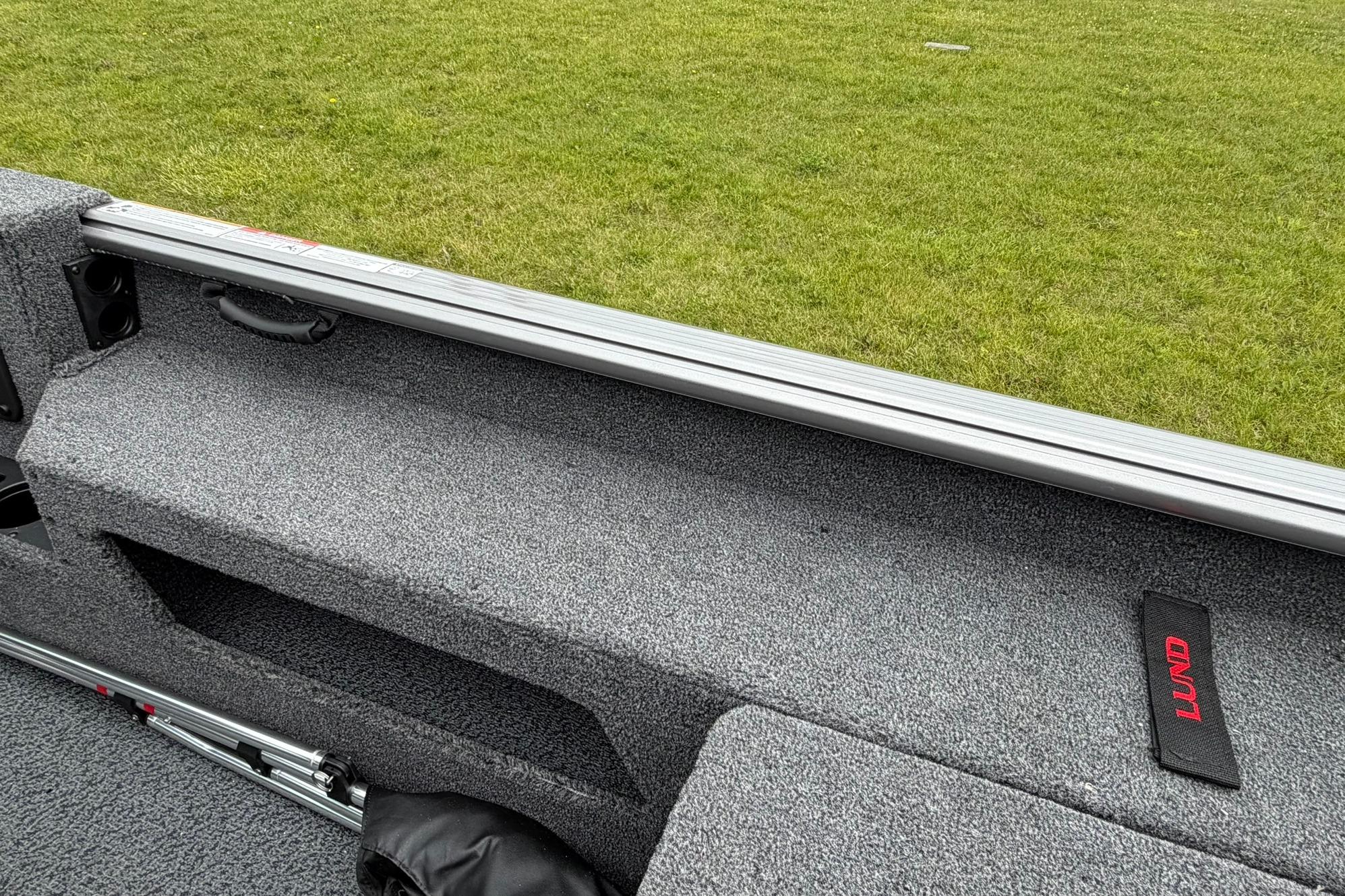 Interior view of 2027 Lund 1875 Impact XS Sport boat with gray carpet and storage.