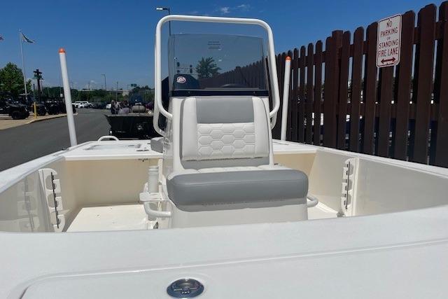2026 Mako 18 Pro Skiff boat with seating, docked near a wooden fence.