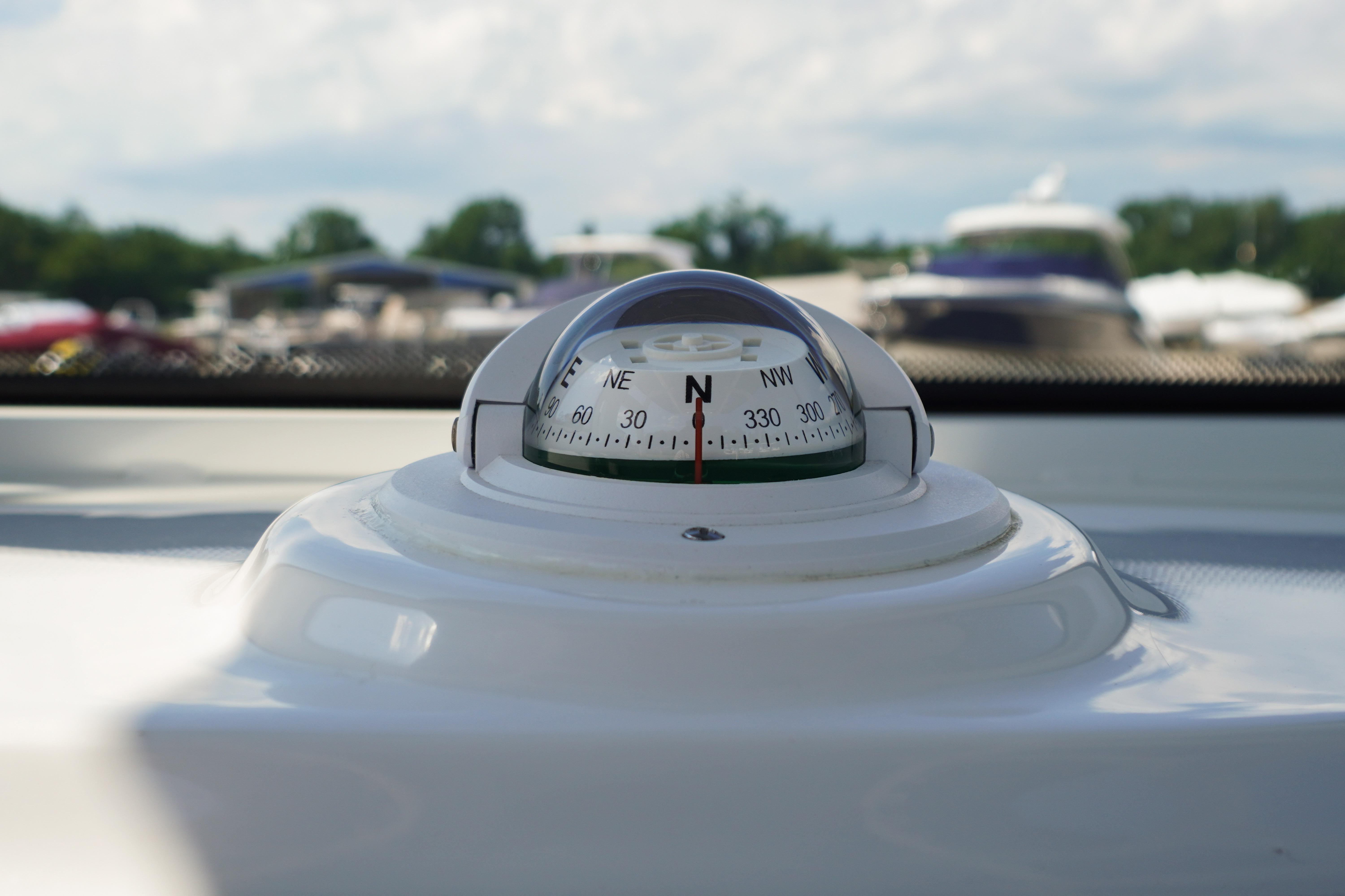 Compass on 2025 Tidewater 232 SS boat, with blurred marina background.