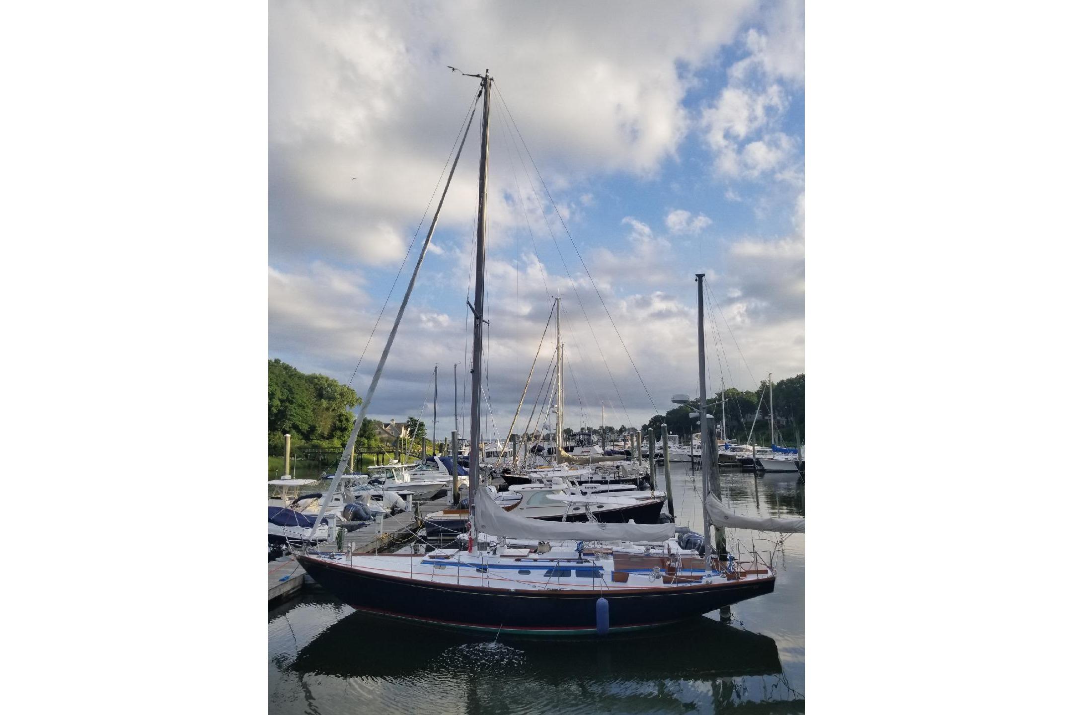 1970 Hinckley Bermuda 40 sailboat docked in a marina under a partly cloudy sky.