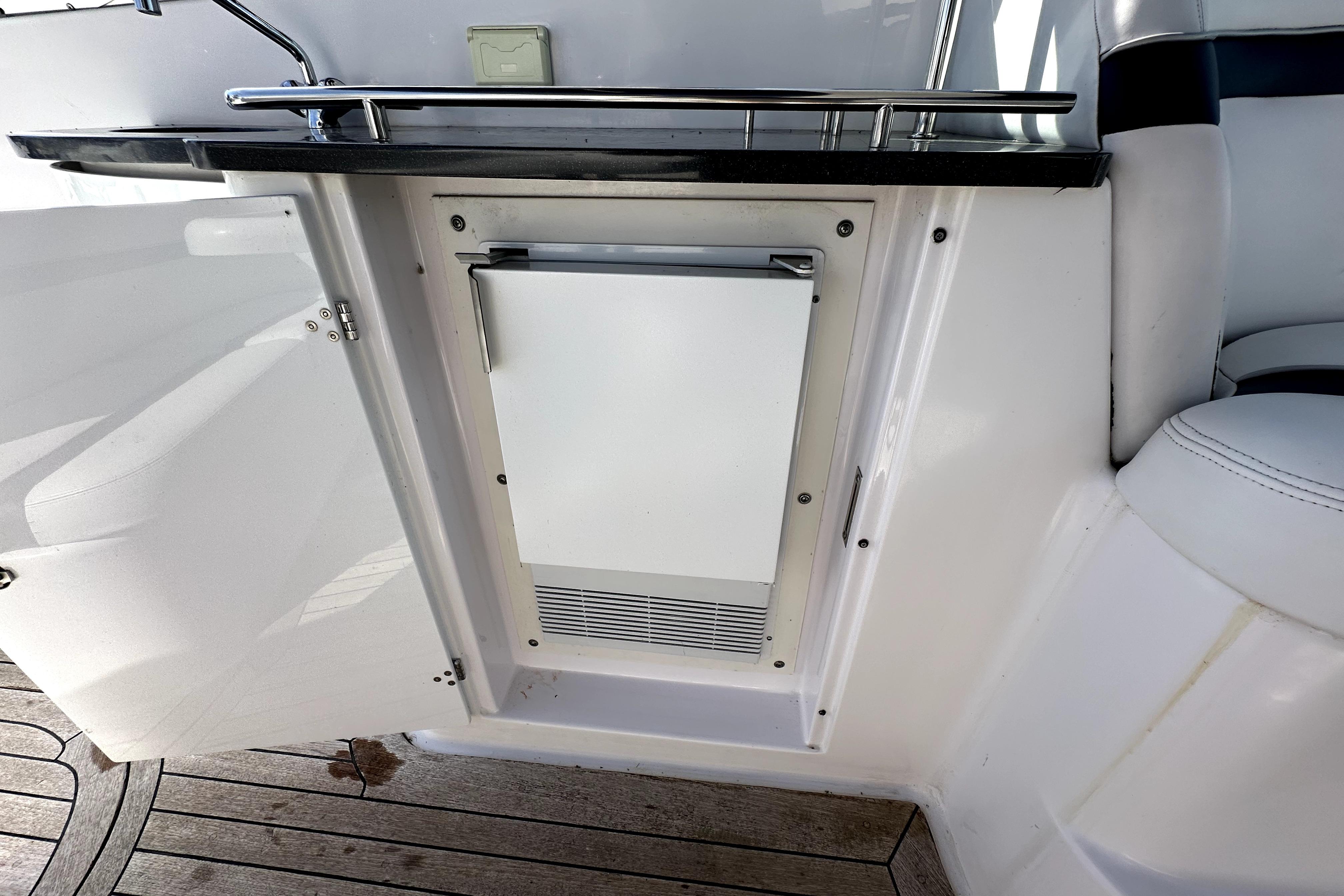 2003 Donzi 39 ZSC boat interior with compact refrigerator and sleek white cabinetry.