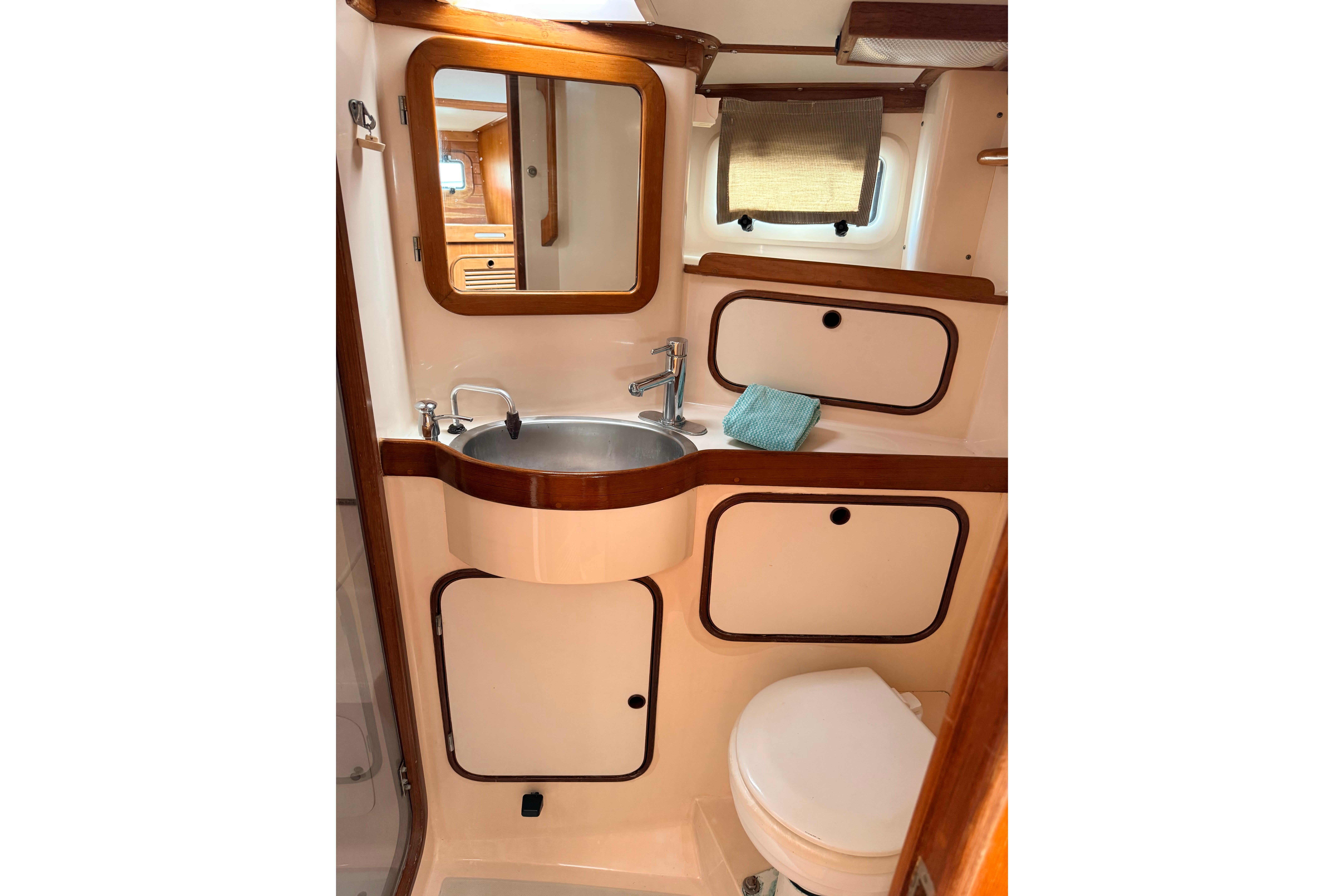 Compact bathroom in 1987 Norseman 400 yacht with sink, mirror, and storage cabinets.