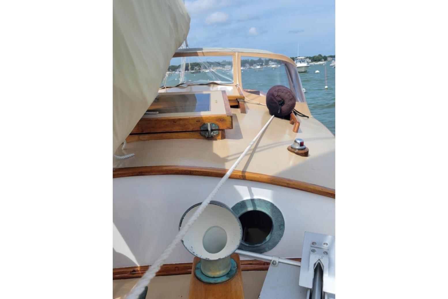 1978 Cape Cod Catboat, Ted Brewer model, docked with scenic harbor view.
