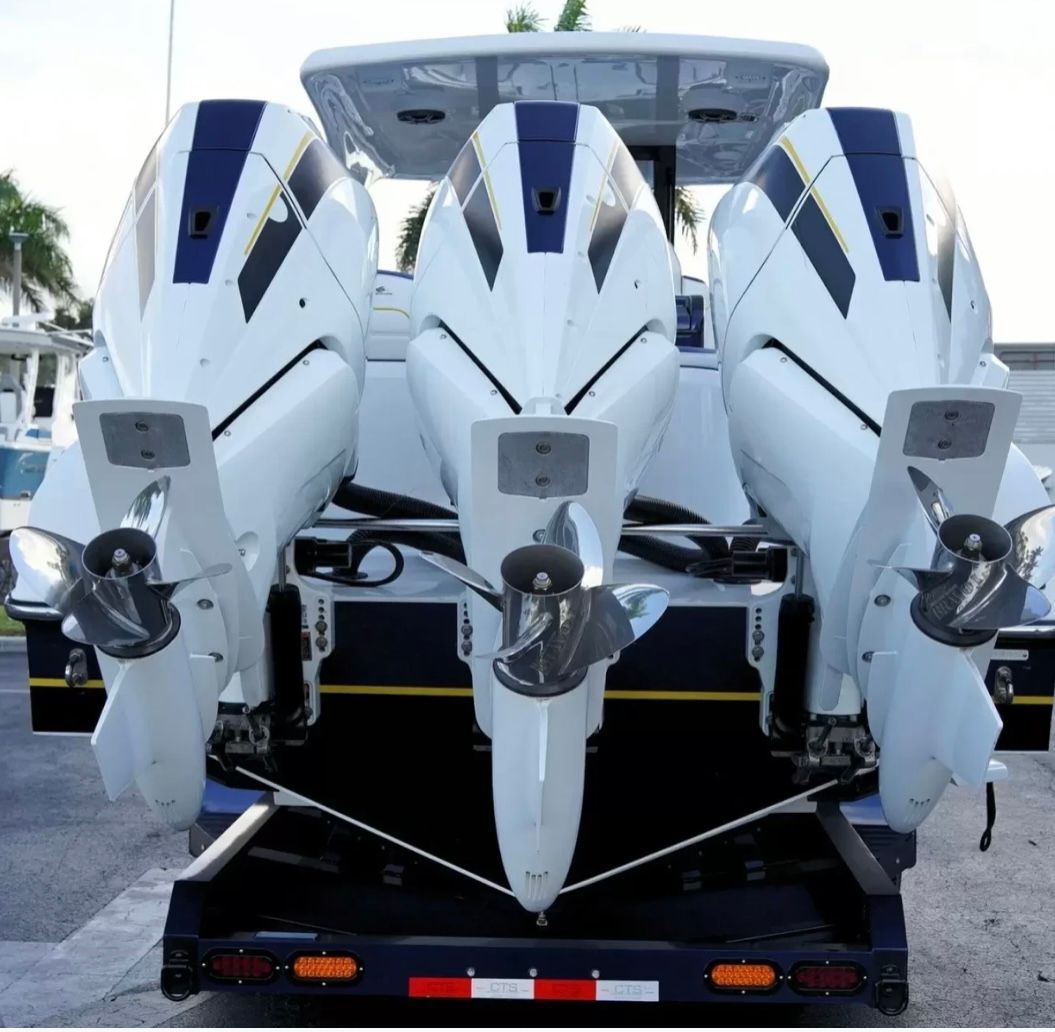 Three powerful outboard engines are mounted on the stern of a modern boat.
