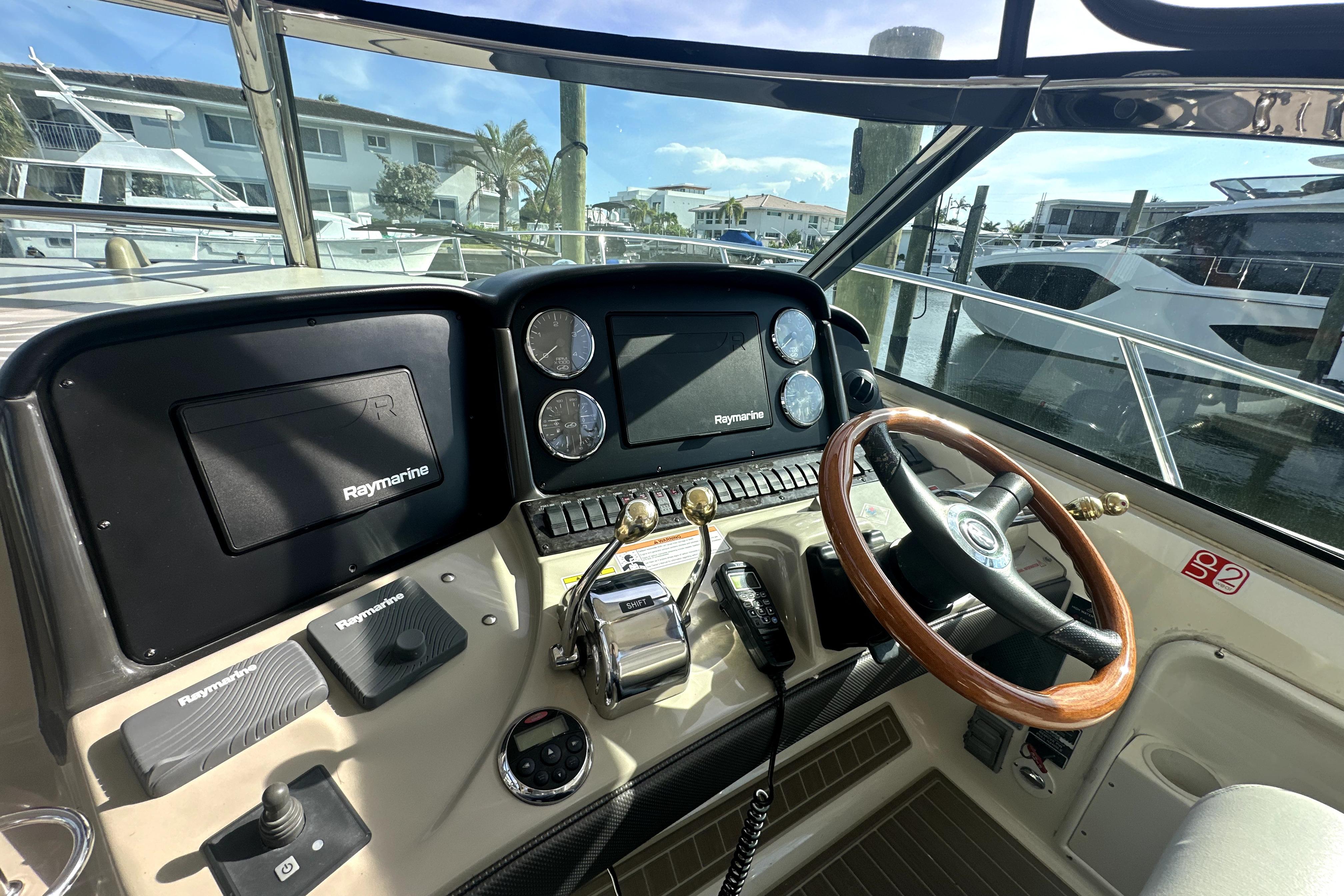 Helm of 2007 Sea Ray 44 Sundancer with Raymarine navigation system and wooden steering wheel.