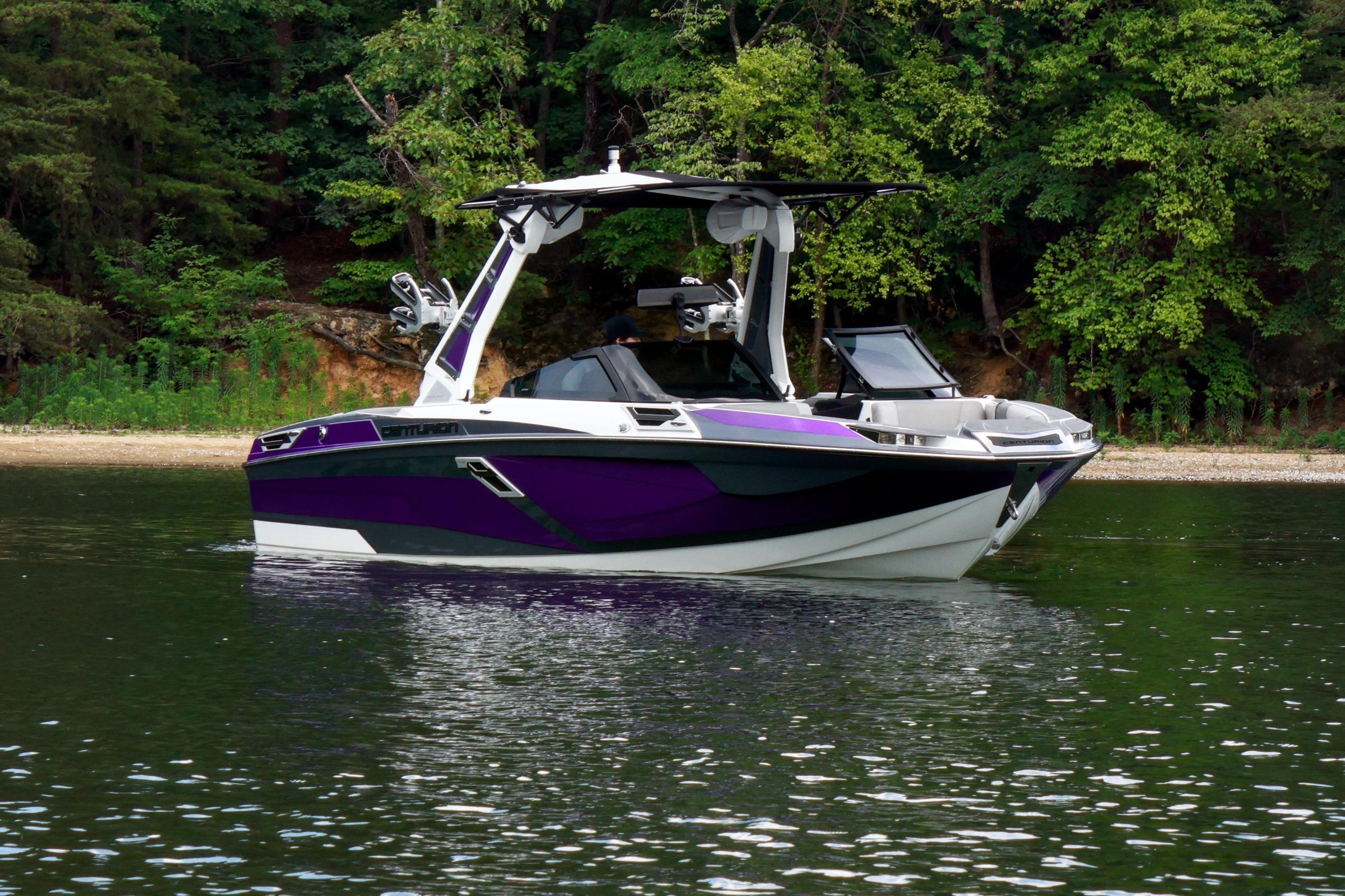 2022 Centurion Ri245 boat with purple accents on a calm lake near a forested shoreline.