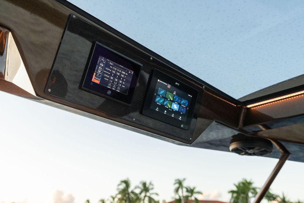 Control panel of 2023 DeKoning 43 boat with digital displays and scenic background.