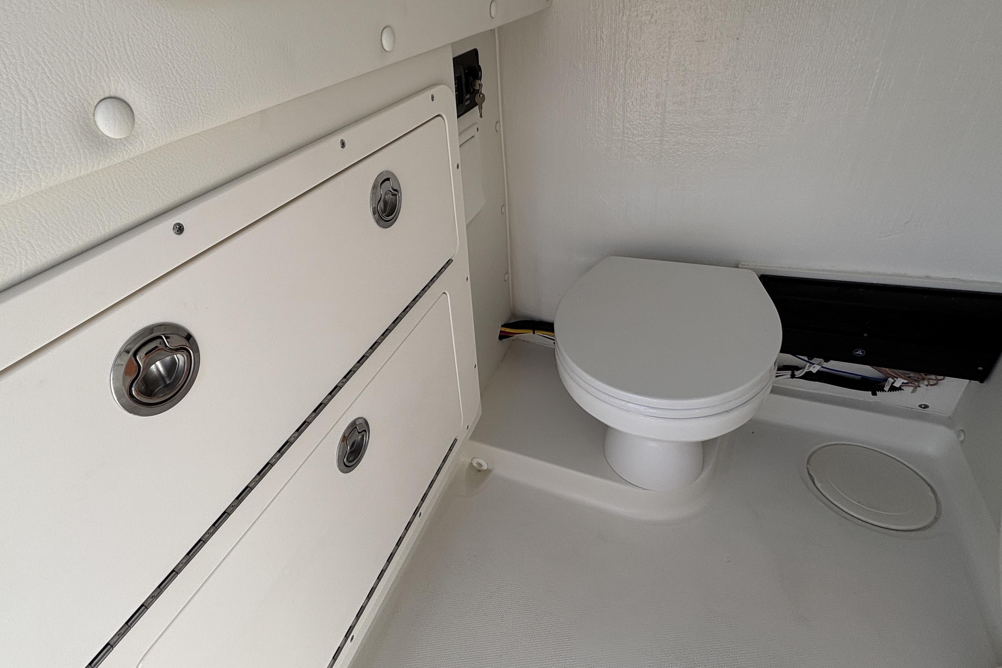 Interior of 2026 World Cat 325 CC boat featuring a compact marine toilet.