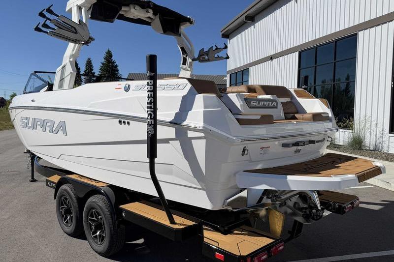 2026 Supra SL boat on trailer, parked near a modern building.