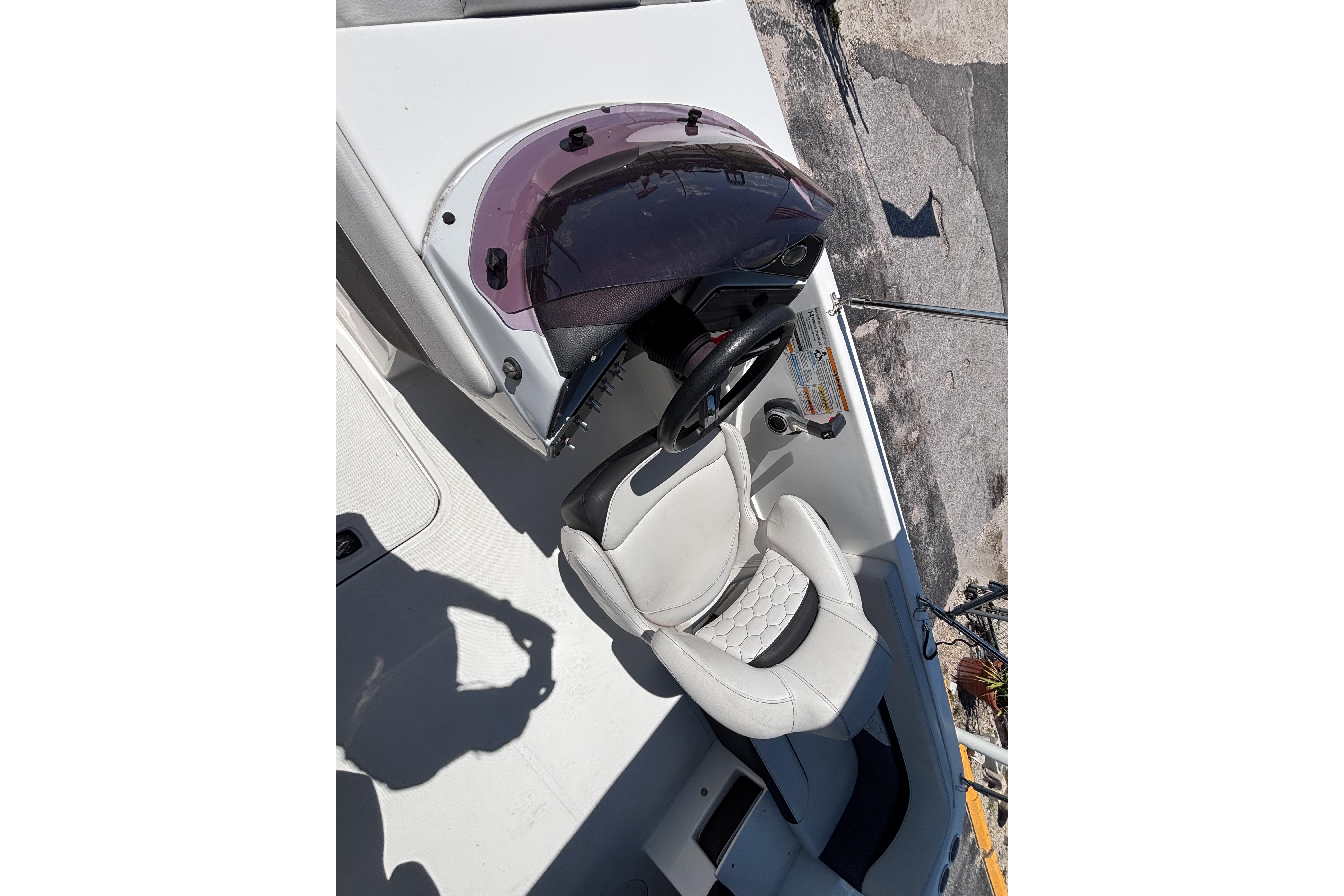 2019 Hurricane Sundeck Sport 218 OB boat cockpit with steering wheel and white seating.