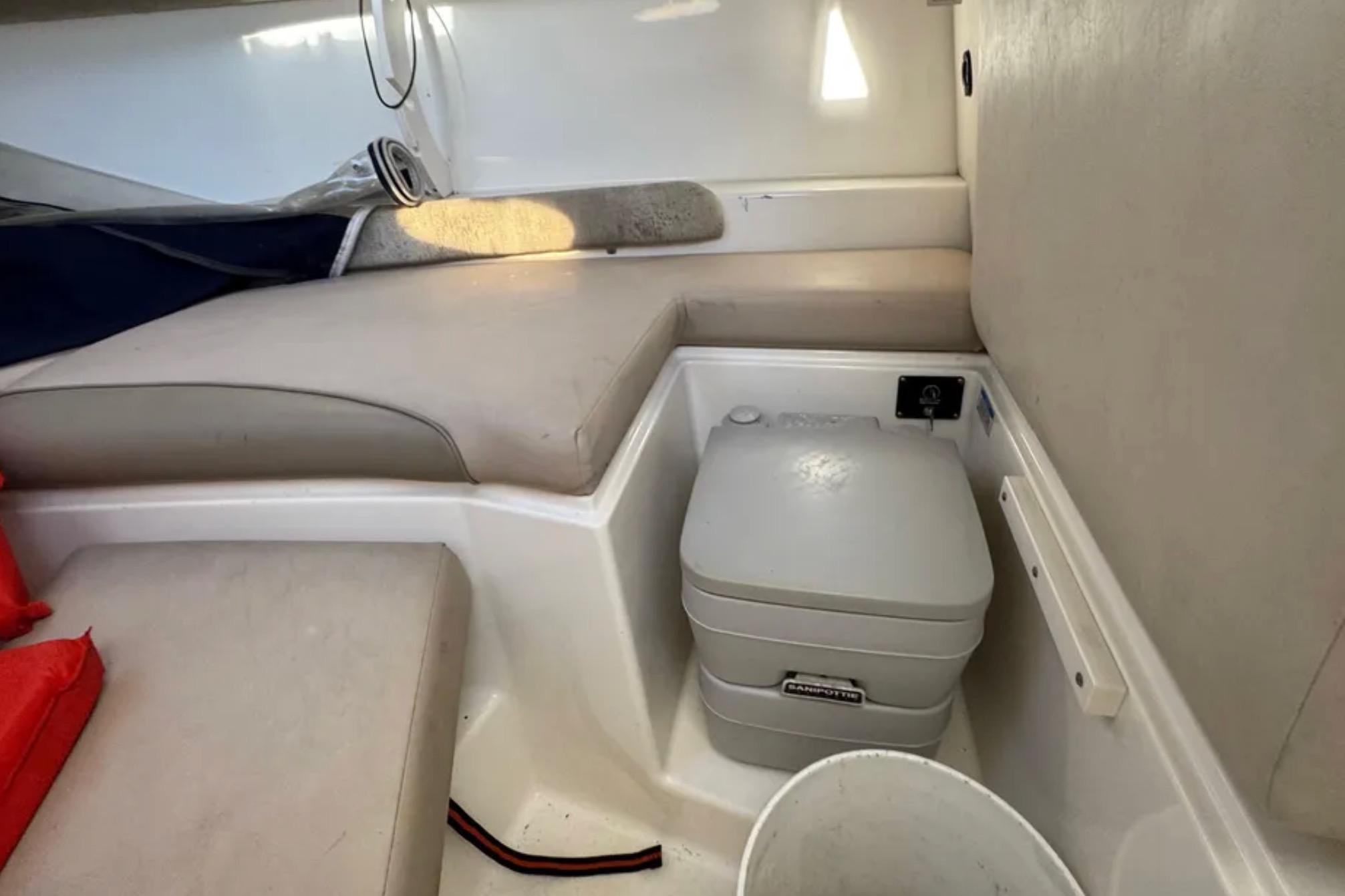 2004 Boston Whaler 255 Conquest cabin interior with seating and portable toilet.