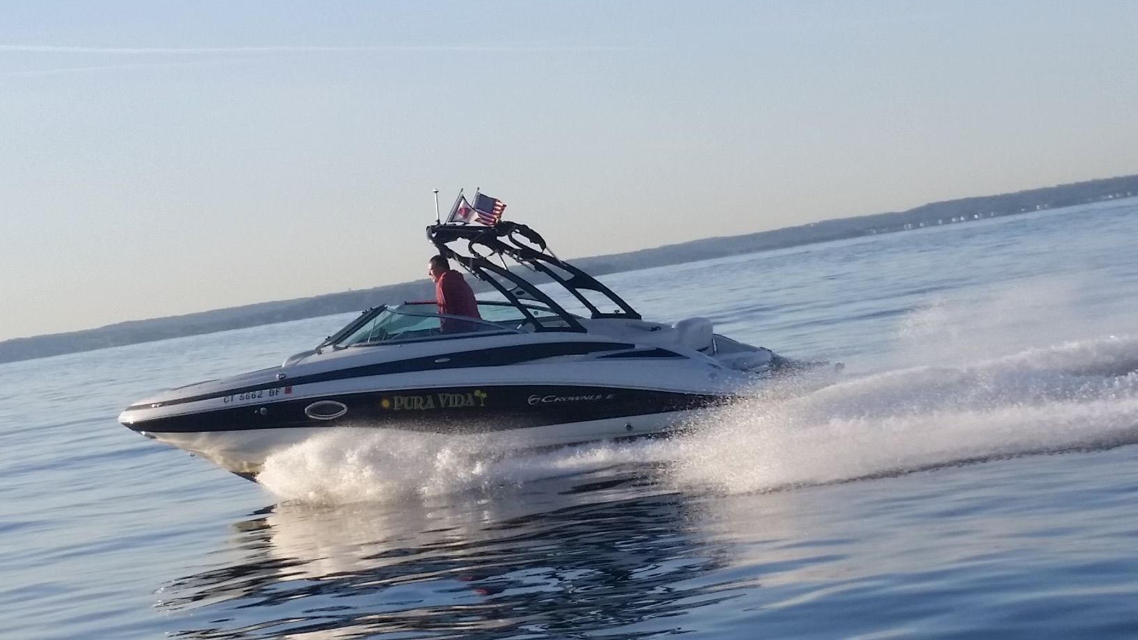 A 2013 Crownline E-4 Bowrider speeding across calm water.