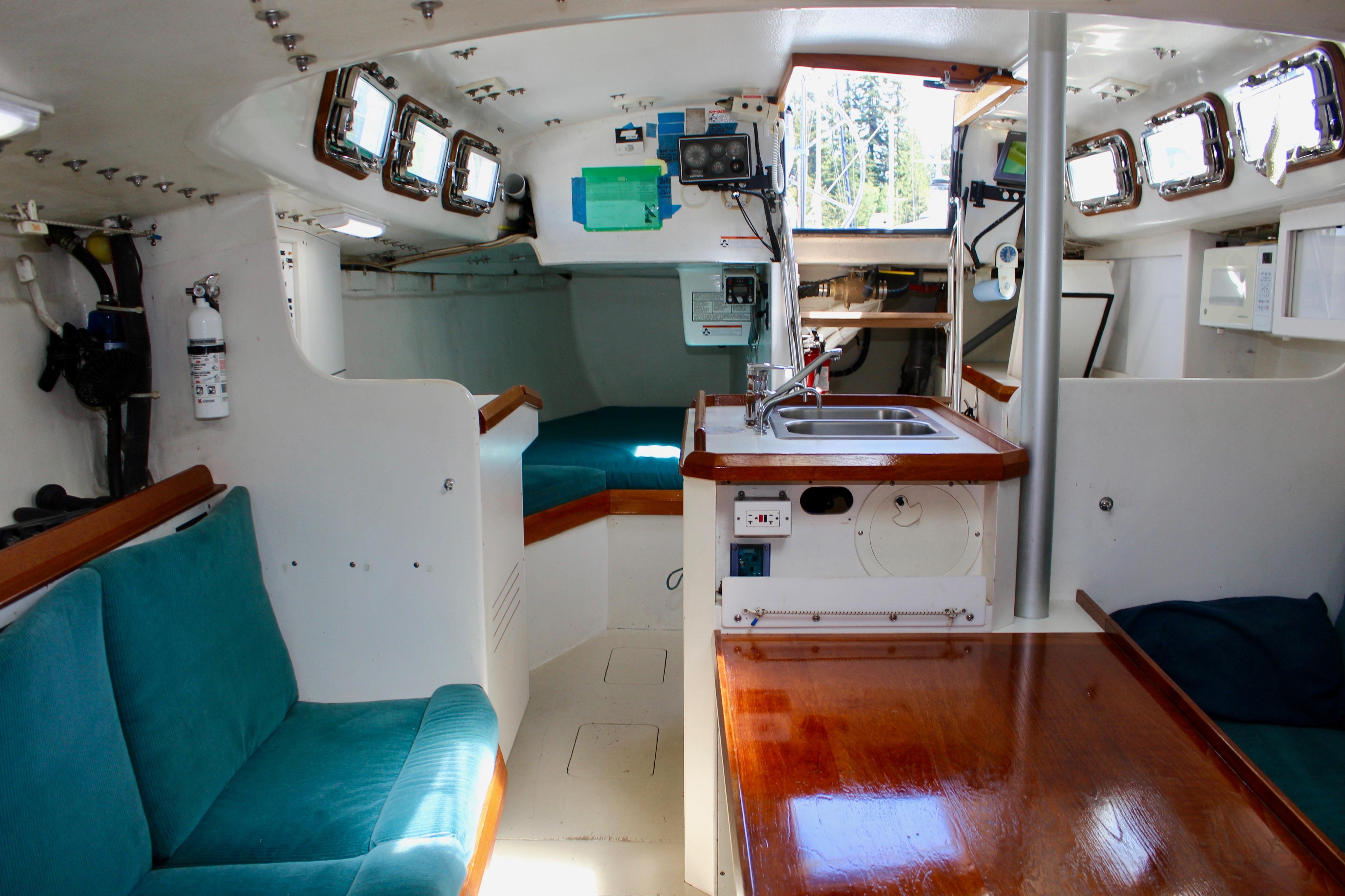 Interior of a 1993 Freya 39 sailboat with teal seating and wooden accents.
