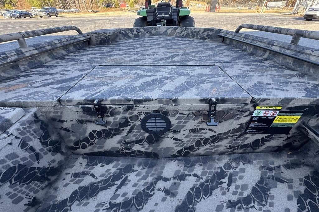 Camouflage-patterned interior of a 2025 Havoc 1860 boat, featuring storage compartments and safety labels.