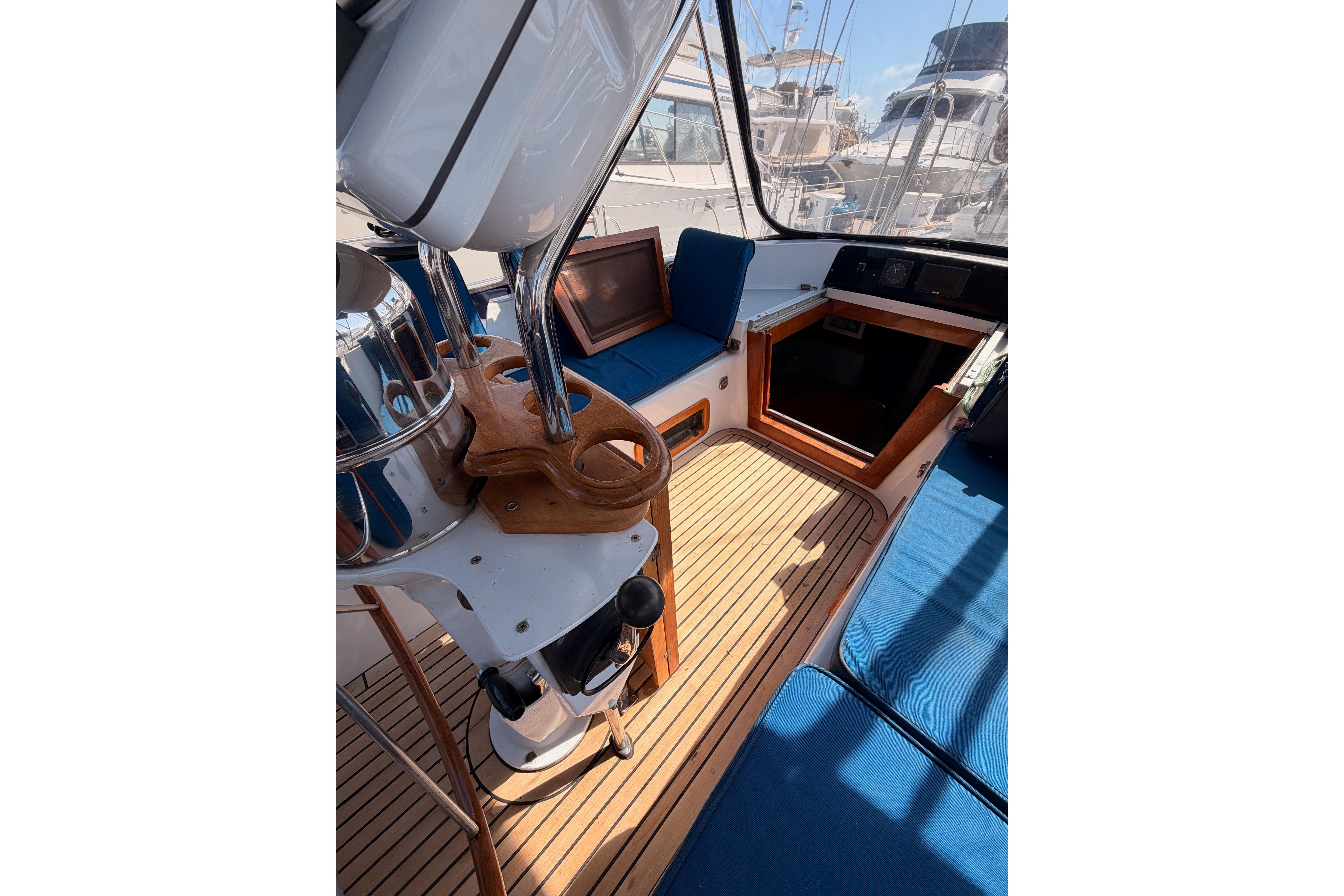 Interior view of a 1991 Hylas 51 yacht cockpit with wooden flooring and blue seating.