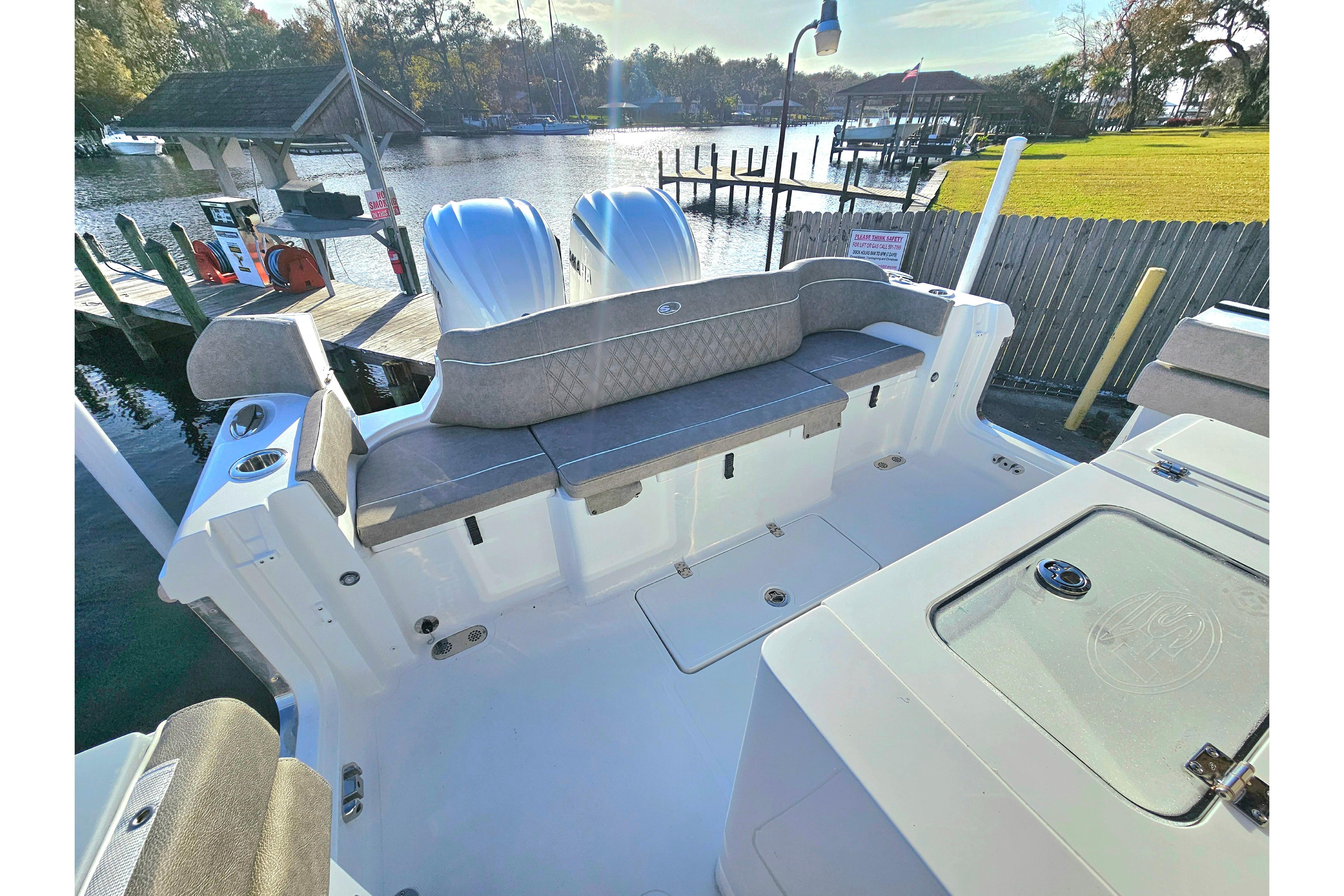 2026 Sea Hunt Ultra 285 SE boat interior with seating, docked by a scenic waterfront.