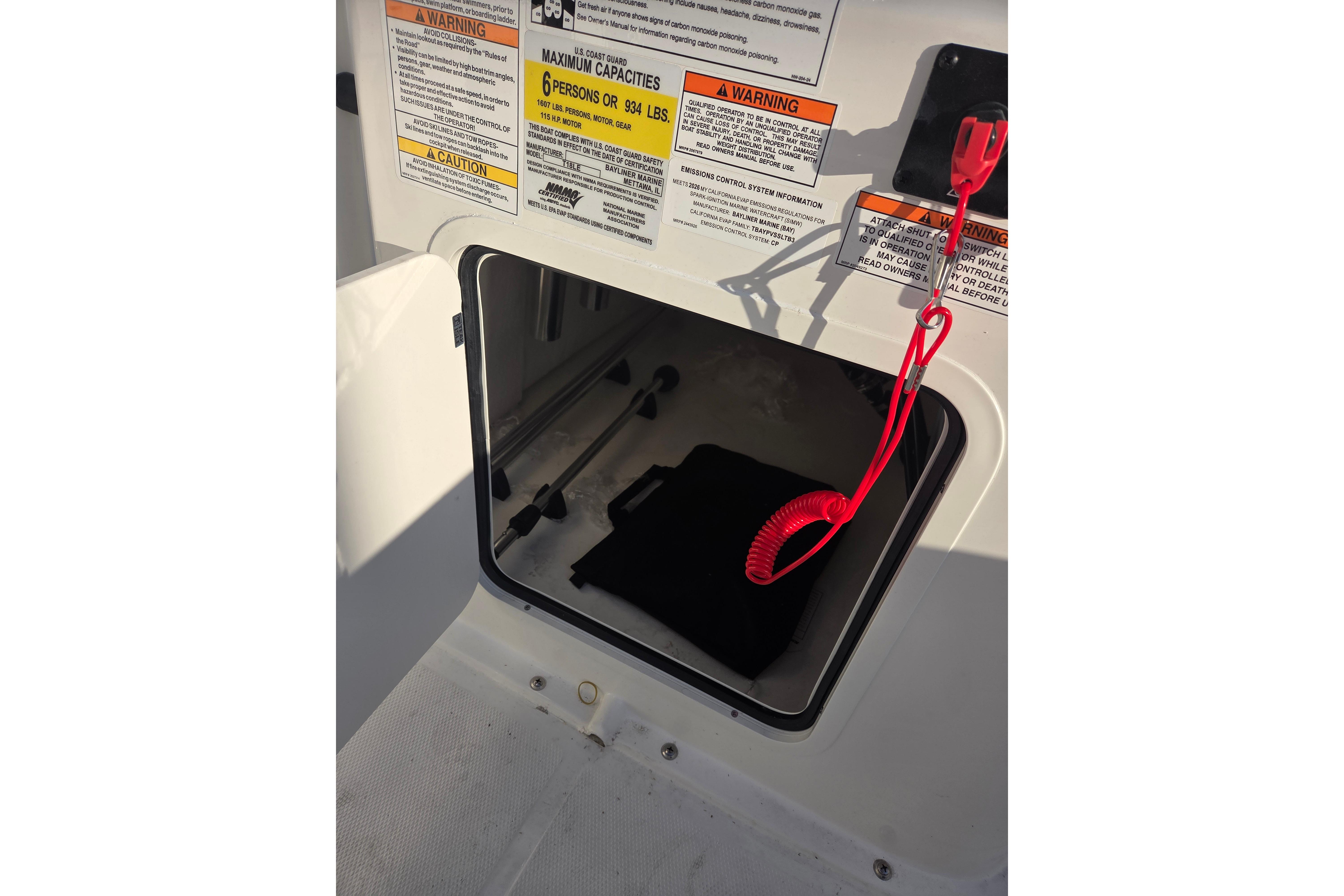 2026 Bayliner Trophy T18 storage compartment with safety warnings and red safety cord.