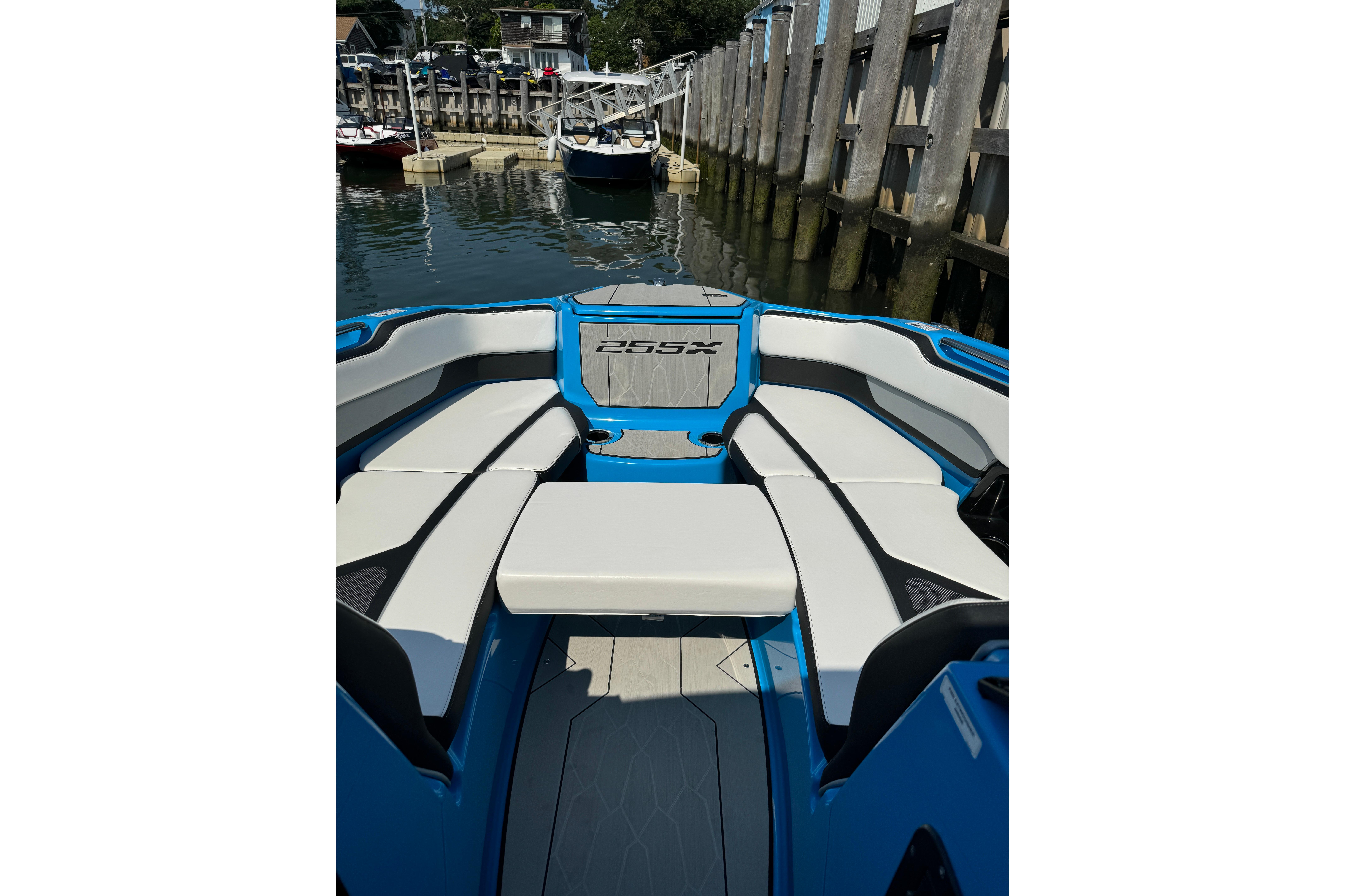 2023 Yamaha Boats 255XD interior with sleek seating, docked by wooden pier.