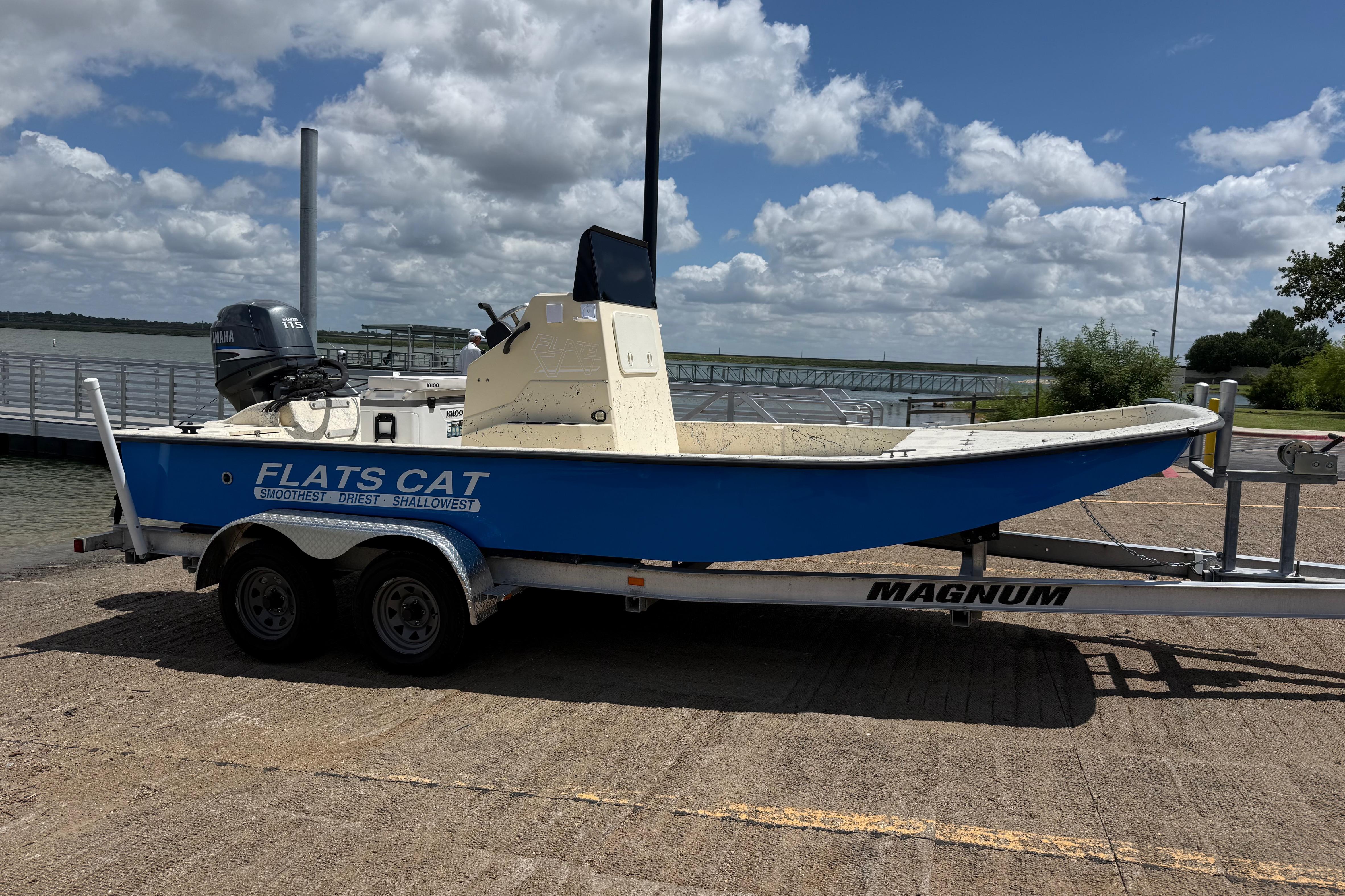 Blue 2007 Flats Cat 19 boat on trailer by waterfront under cloudy sky.