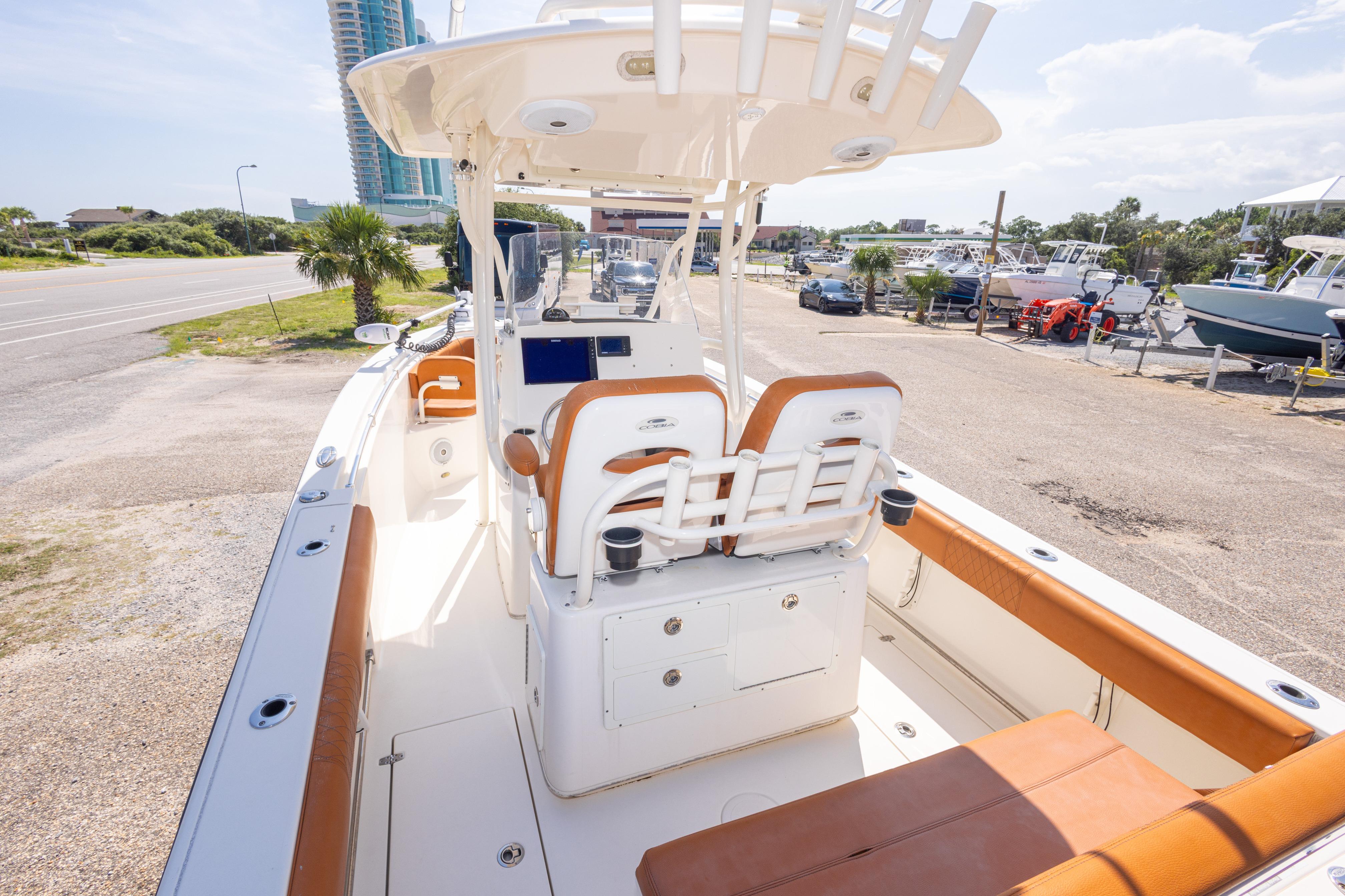 2017 Cobia 261 Center Console boat with tan seating, docked near a coastal road.