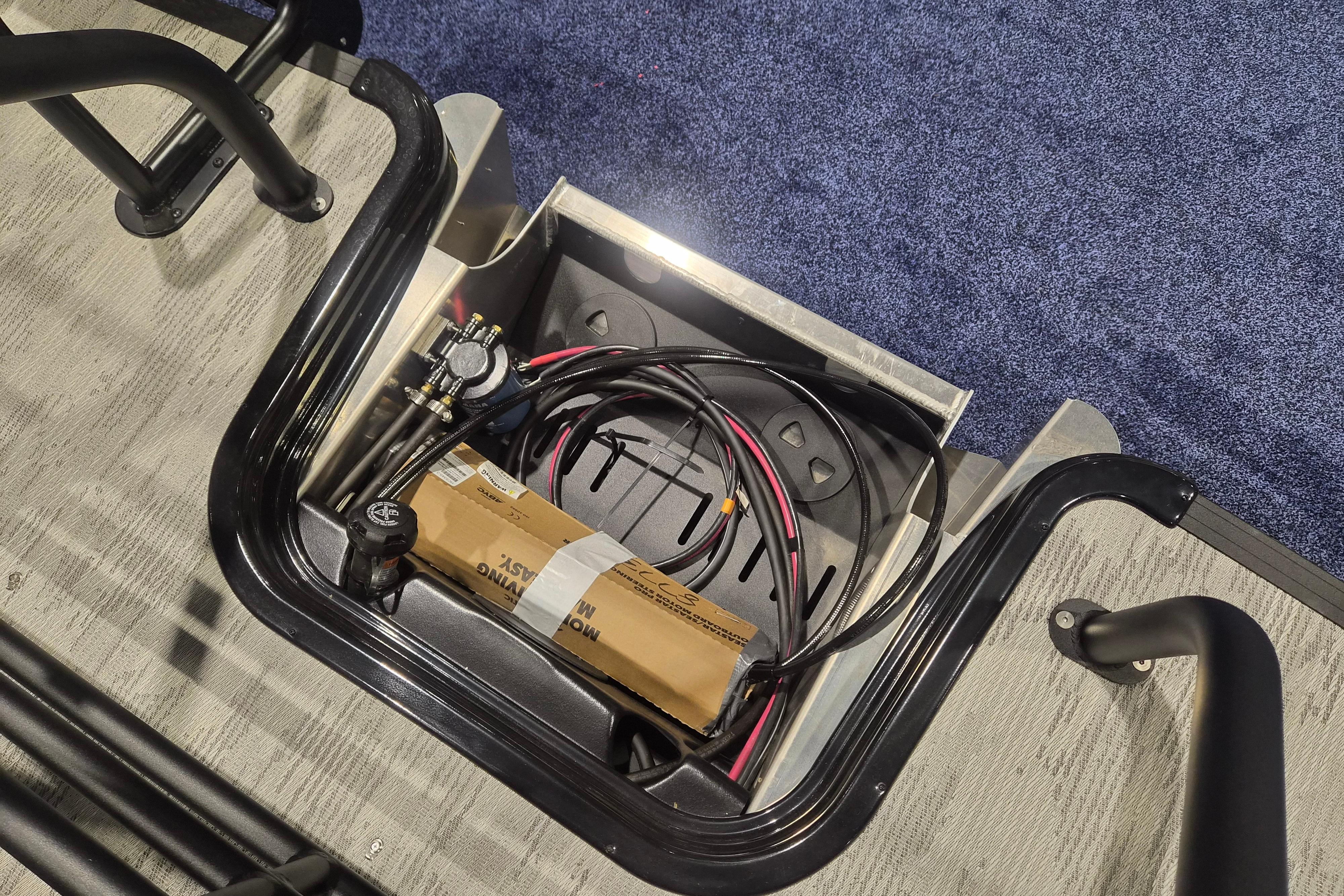 Storage compartment of 2026 Sylvan L3 ULZ with cables and a box.