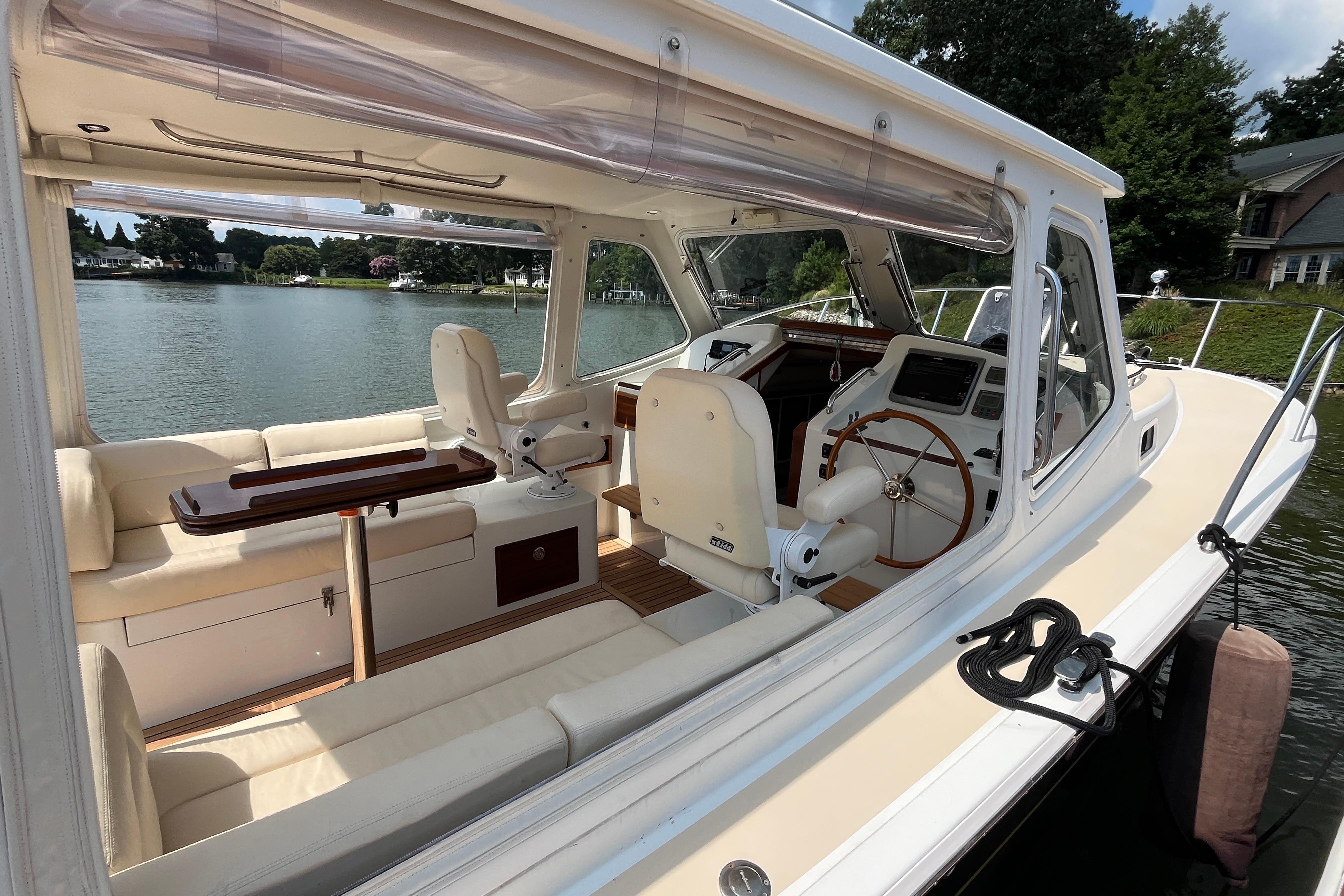 2006 MJM 34z yacht interior with seating, steering wheel, and scenic lake view.