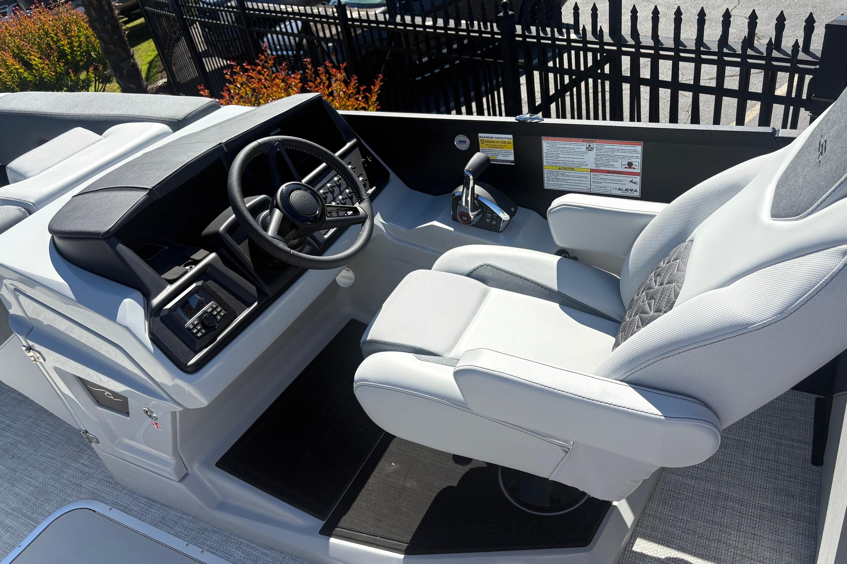 Captain's seat and helm of 2026 Alera 23Q boat, featuring modern controls and steering wheel.