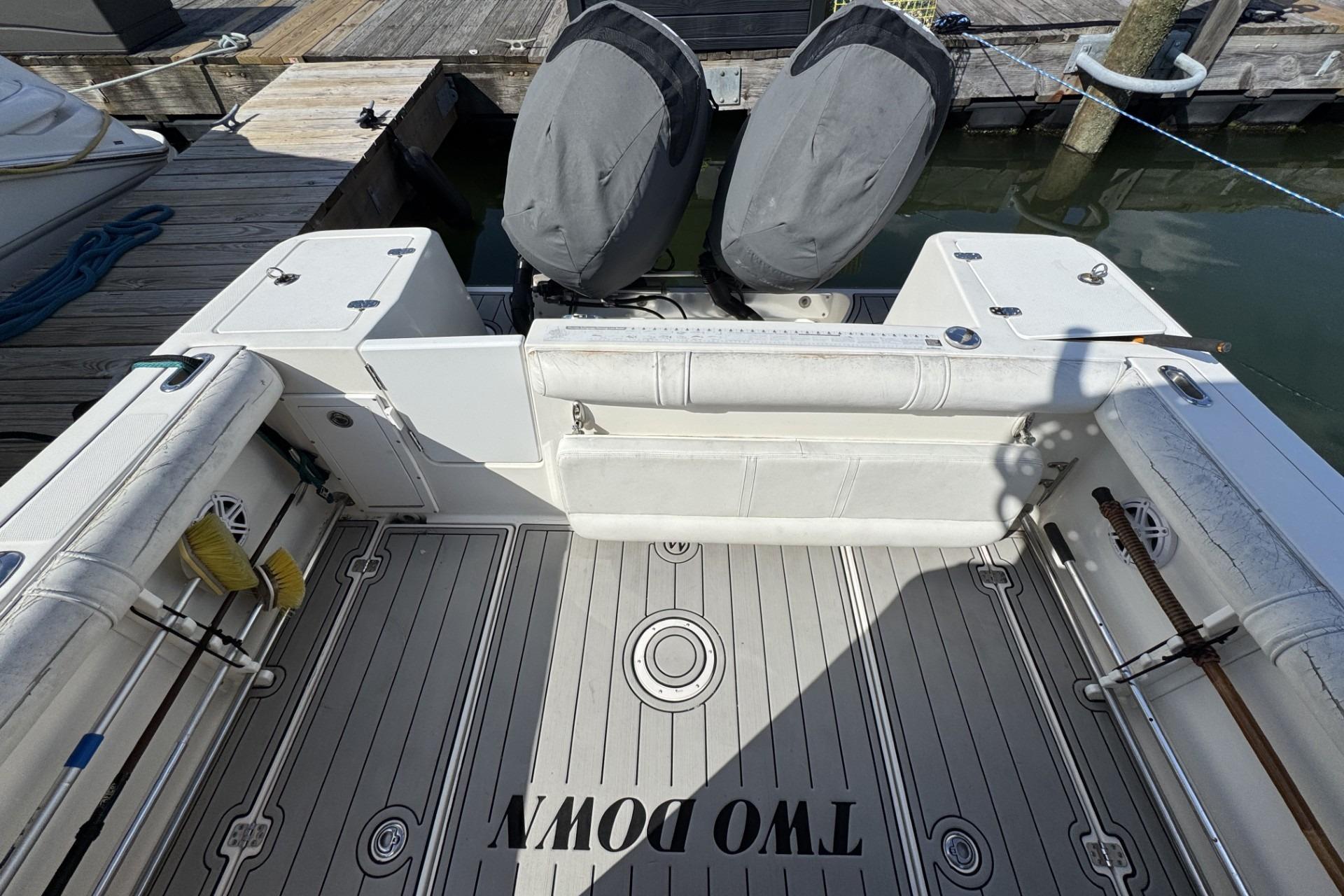 2007 Edgewater 245CC boat deck with twin engines, docked at marina.