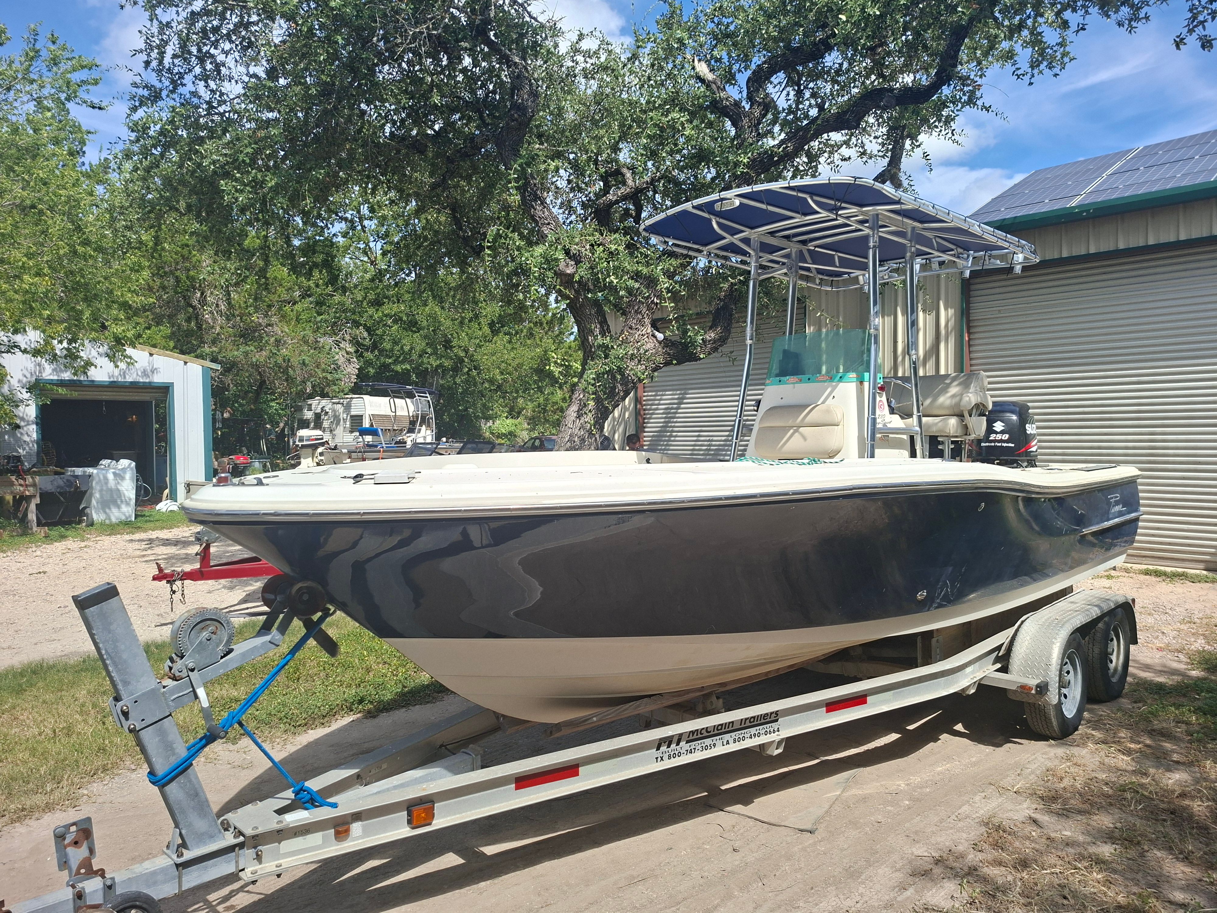 A 2008 Pioneer 220 Bay Sport boat on a trailer in a yard.