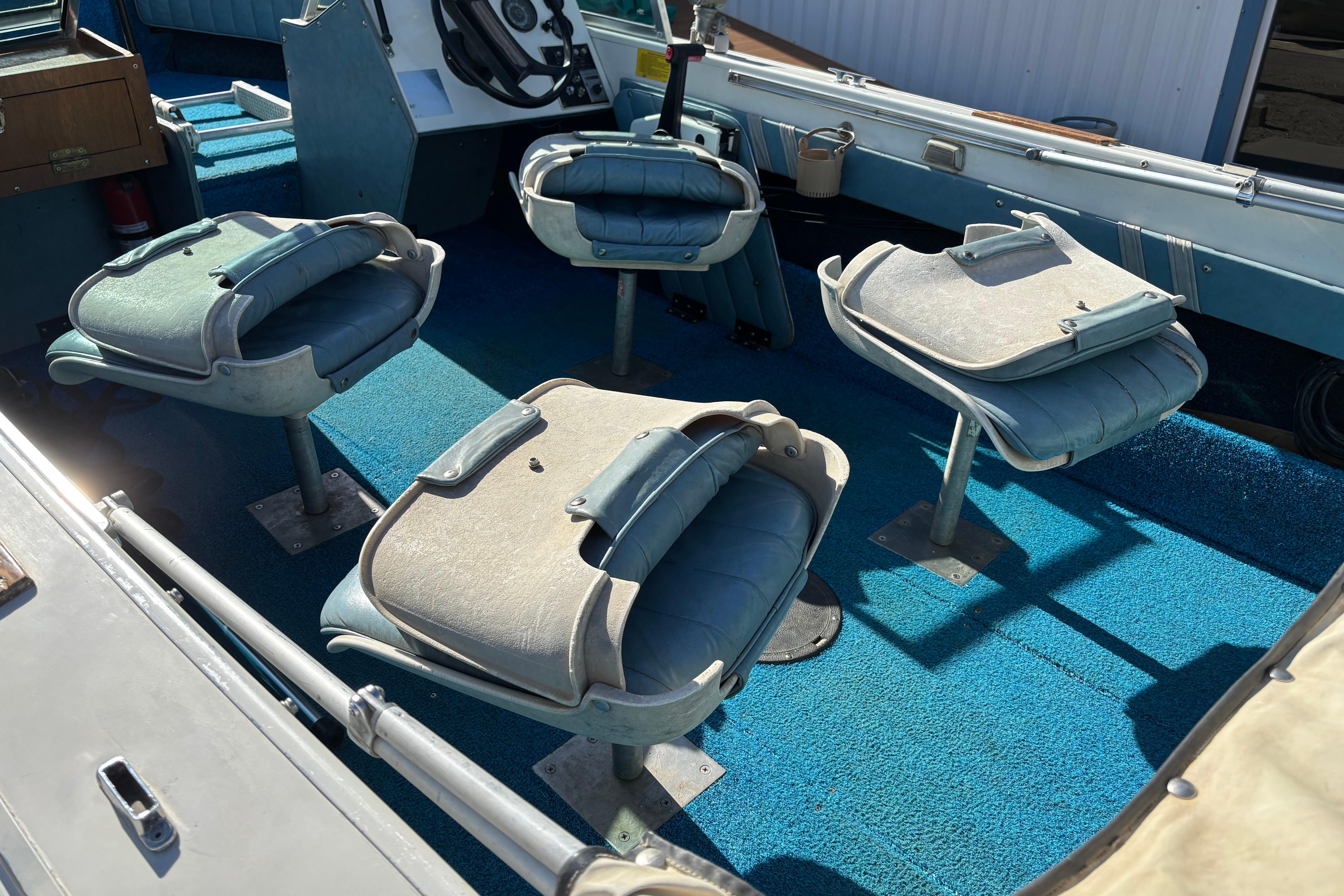1983 Crestliner 16 boat interior with blue carpet and four swivel seats.