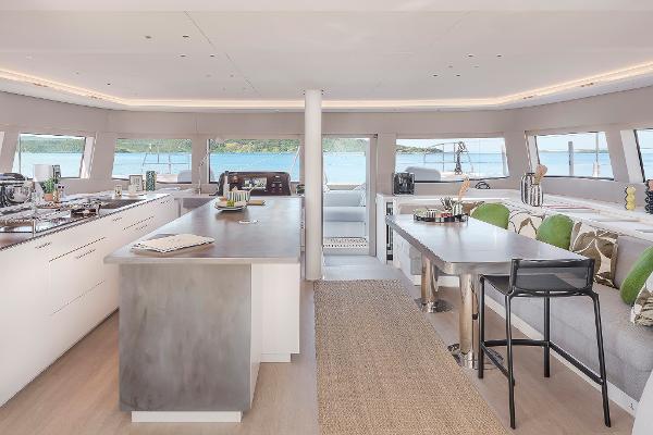 Luxurious interior of 2025 Lagoon SIXTY 5 yacht with modern kitchen and dining area.