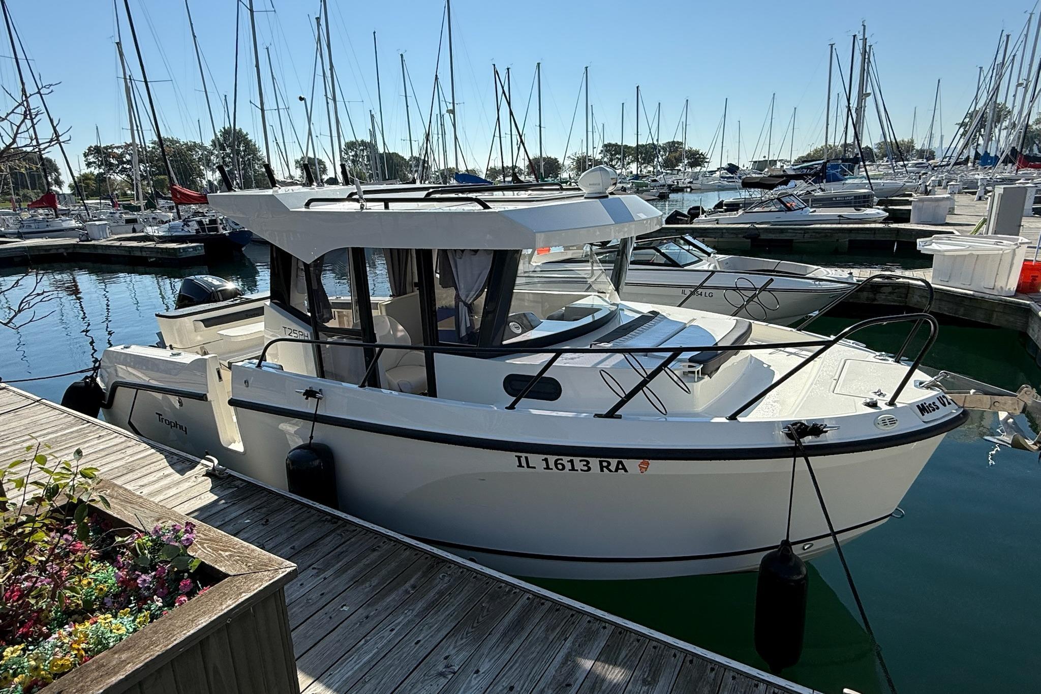 2024 Bayliner Trophy T25 Pilothouse docked in a marina with sailboats.