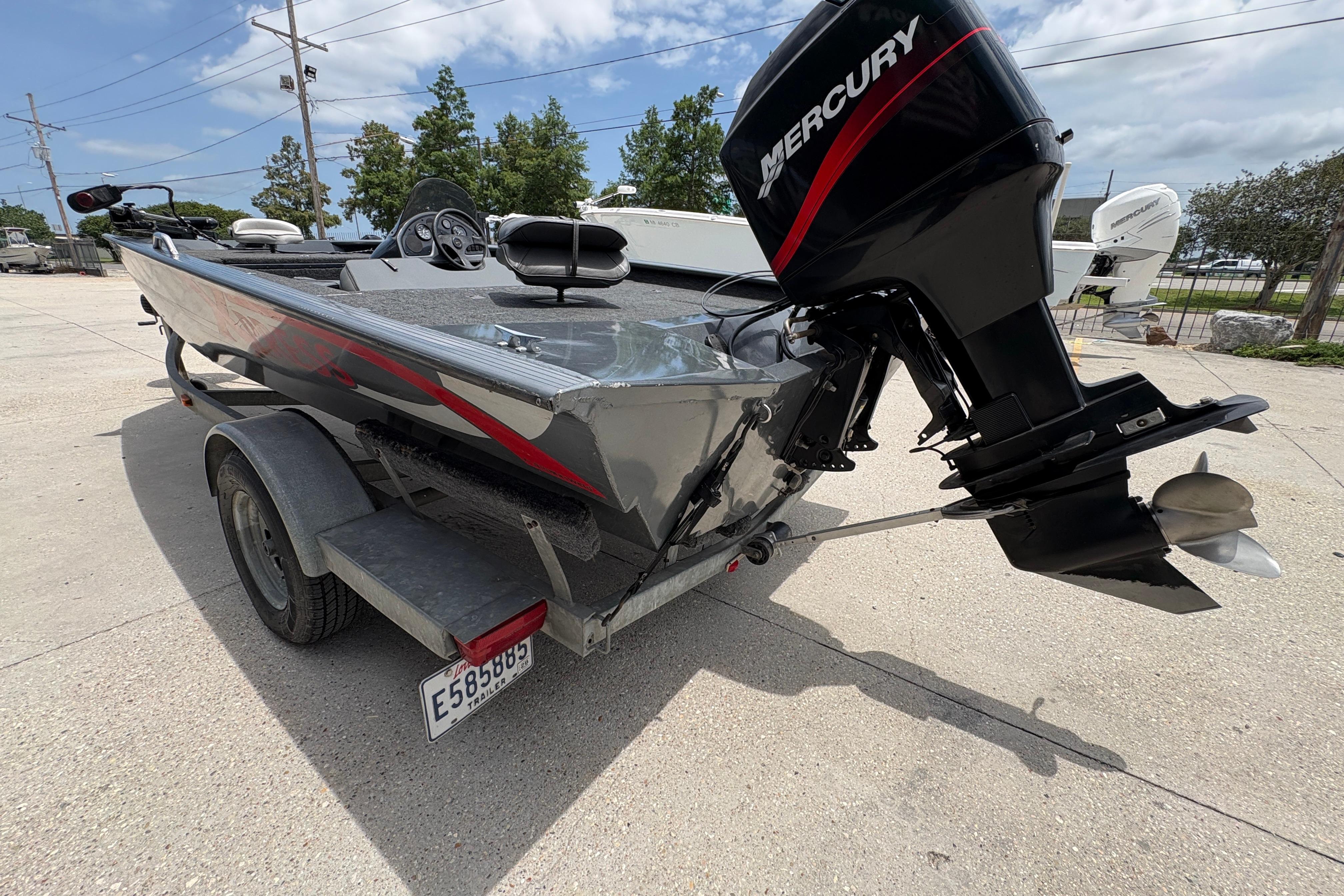 2000 Xpress X18 boat with Mercury outboard motor on trailer, parked outdoors.