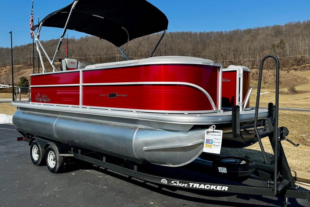 2026 Sun Tracker Party Barge 20 DLX pontoon boat on trailer, red exterior, parked outdoors.