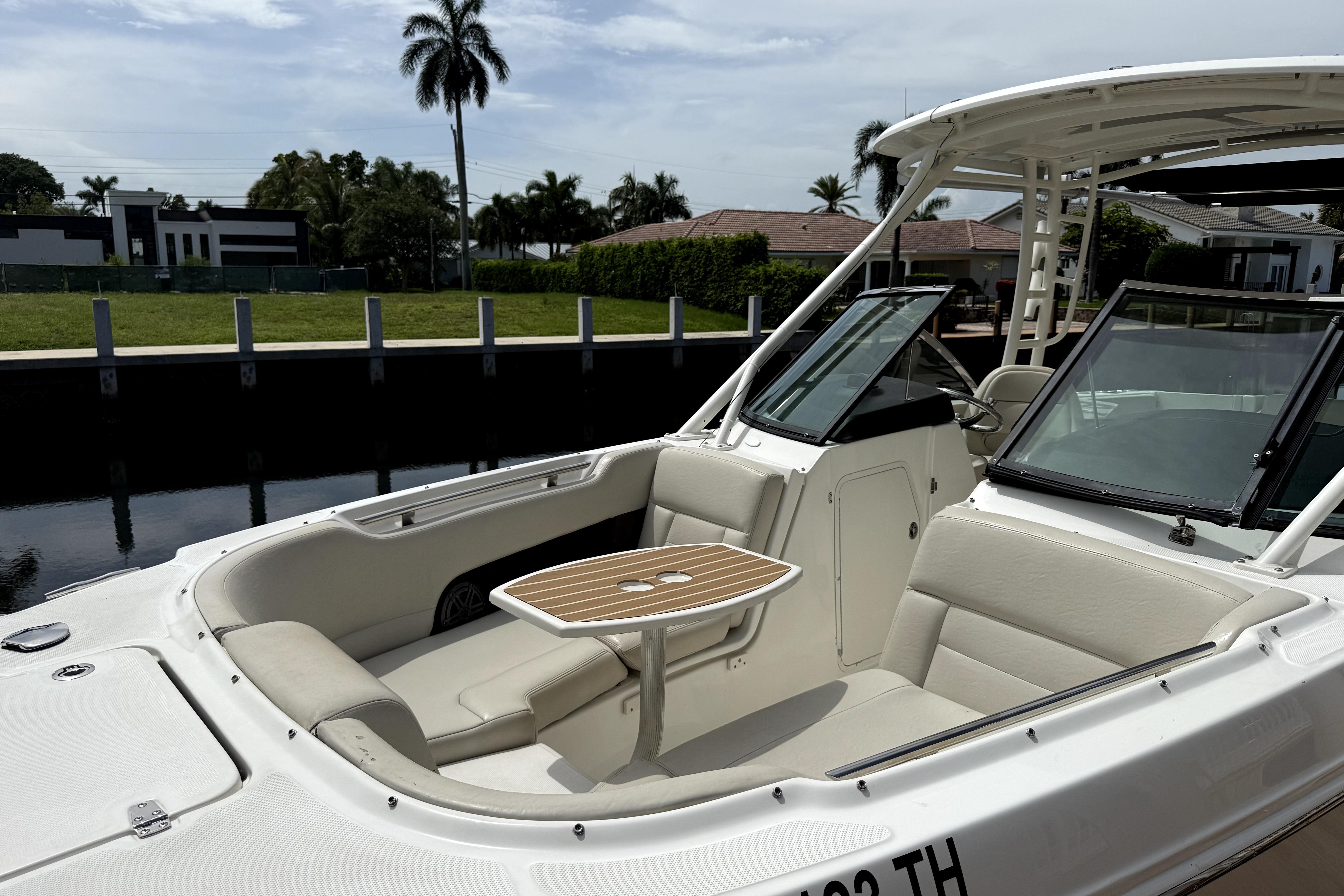 2018 Boston Whaler 230 Vantage boat with seating and table, docked near waterfront homes.