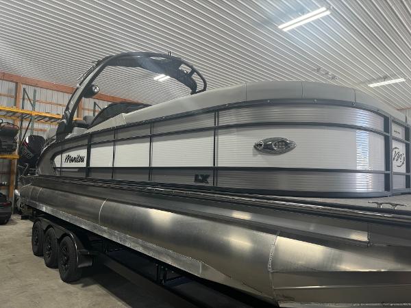 2025 Manitou LX pontoon boat in a storage facility.