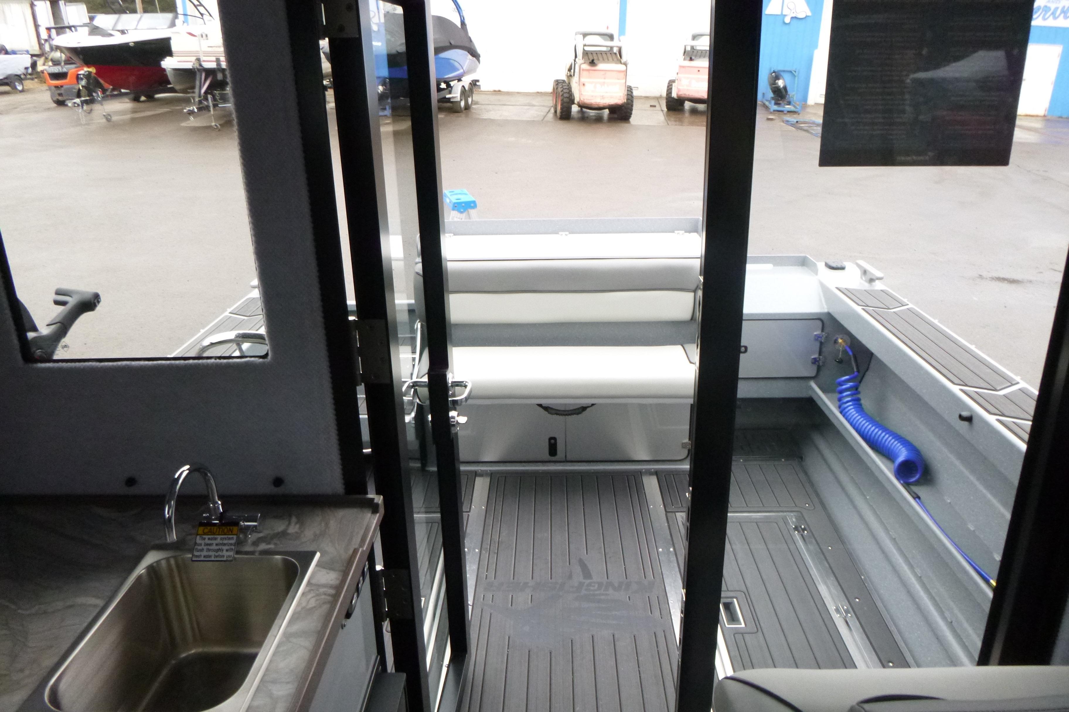 Interior view of 2026 KingFisher 25 XAC boat, featuring seating and a small sink.