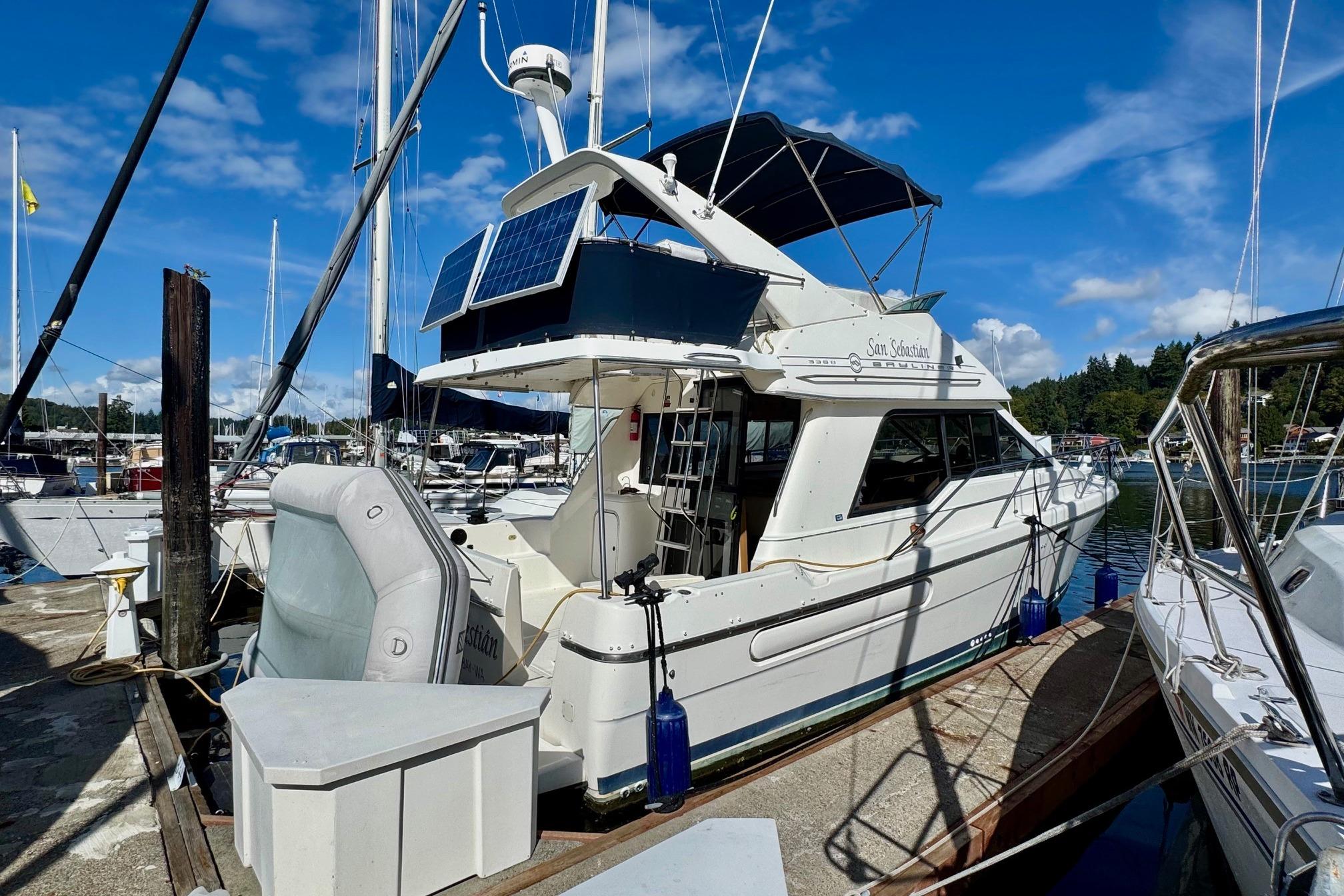 1998 Bayliner 3388 Command Bridge Motoryacht docked at marina under blue sky.