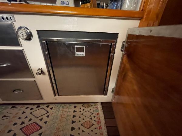 1951 Chris-Craft Catalina interior with stainless steel appliance and wooden cabinetry.