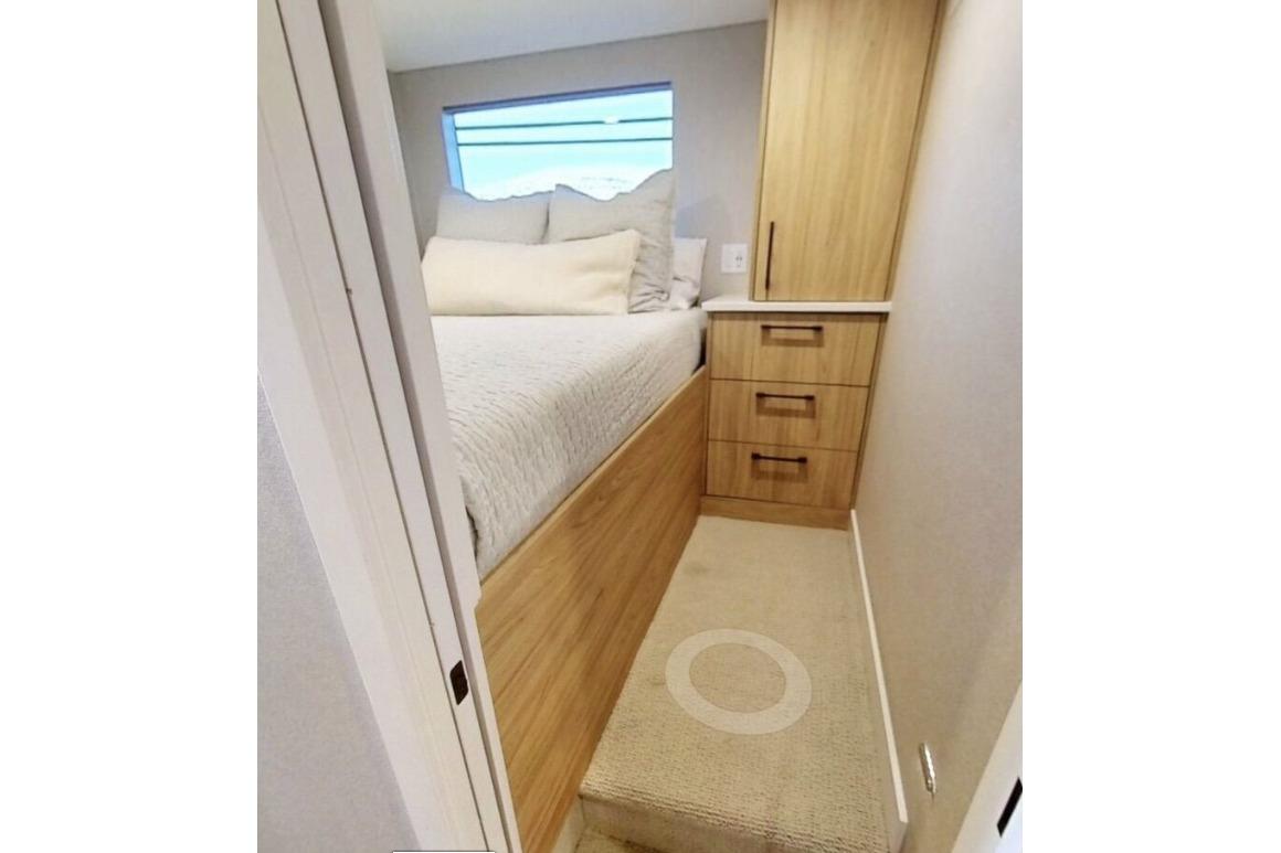 Compact bedroom with wooden storage, cozy bed, and window on Adonia Galileo Trip #1, 2023.