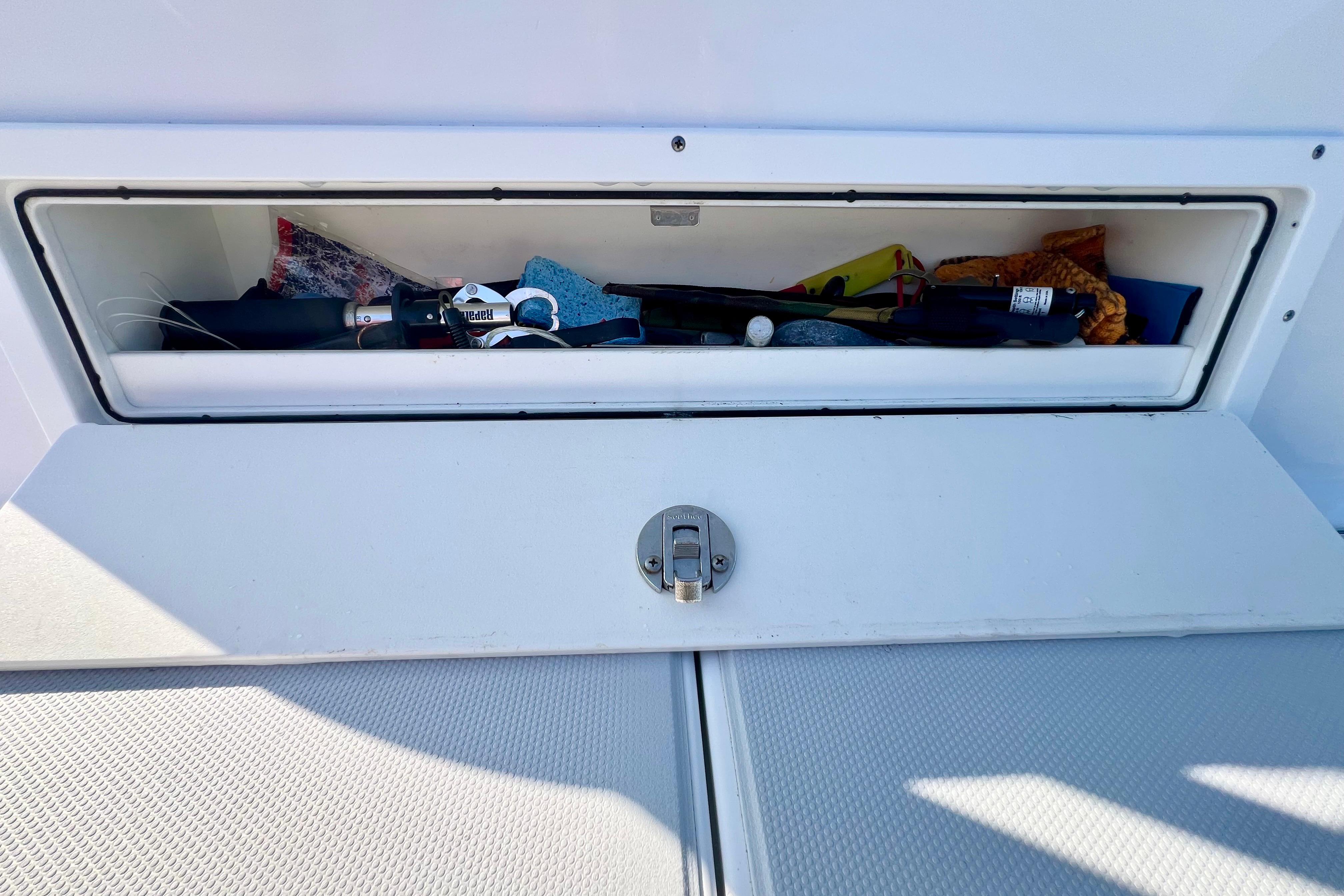 Storage compartment on a 2015 Freeman 34VH boat, containing various tools and items.