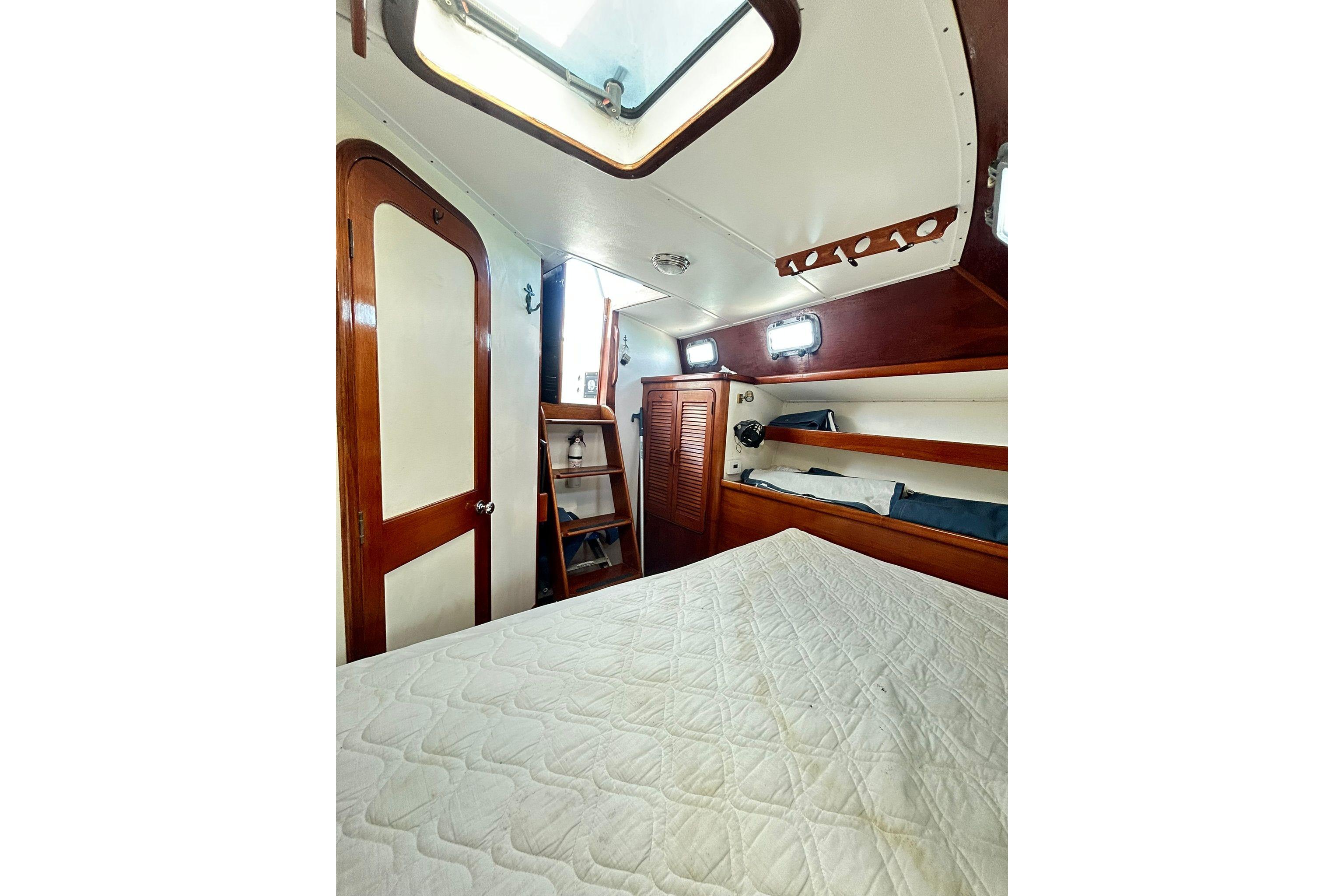 1987 Gulfstar CSY 50 Pilot House cabin interior with bed, wooden shelves, and porthole windows.