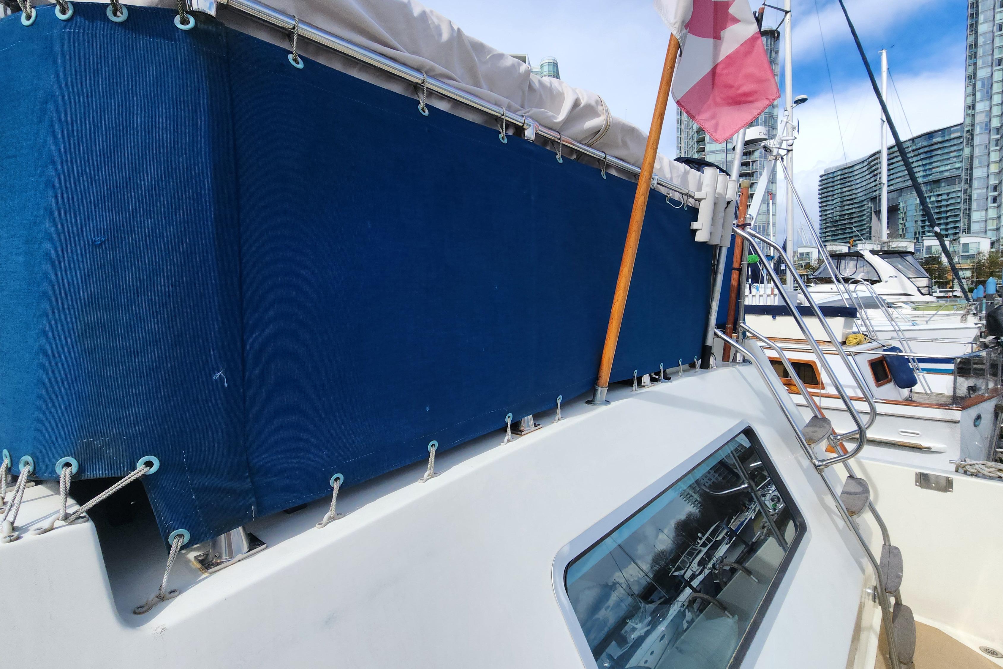 1981 Tollycraft 43 yacht with blue canvas cover and Canadian flag in marina.
