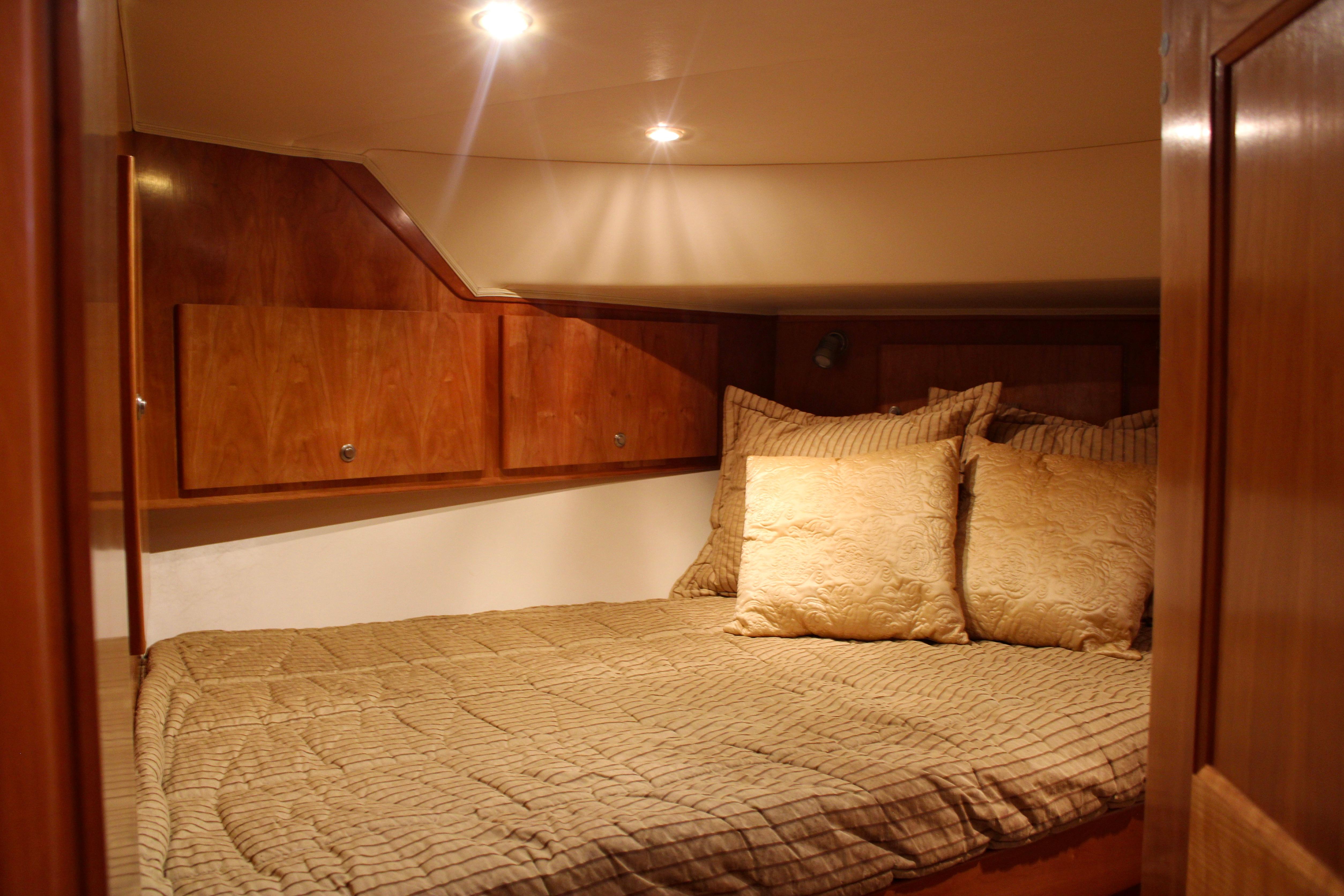 Luxurious cabin interior of 2007 Navigator 5100 yacht with cozy bedding and wooden cabinetry.