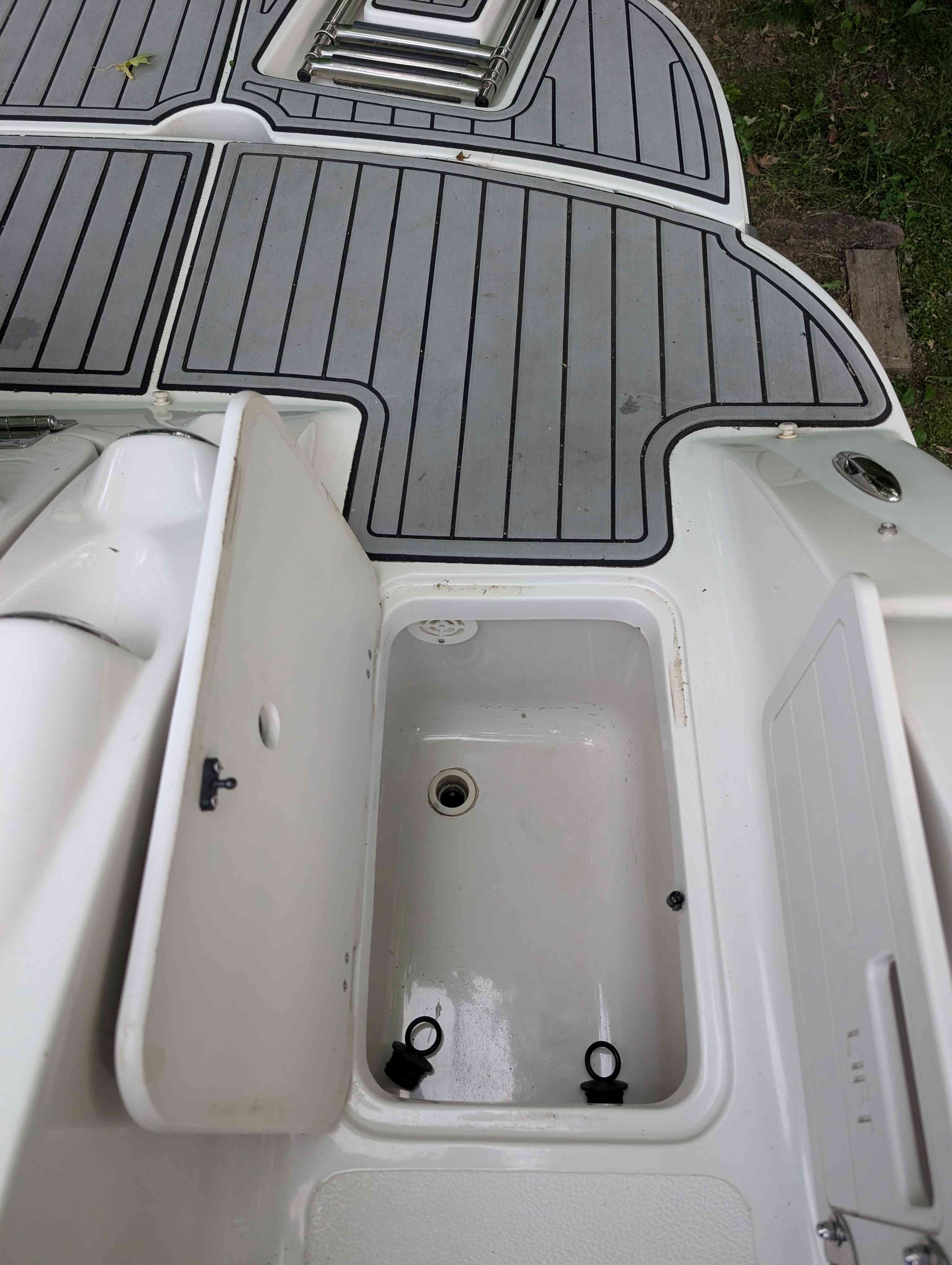 Starcraft 2000 boat, 2015, with open storage compartment and gray deck.