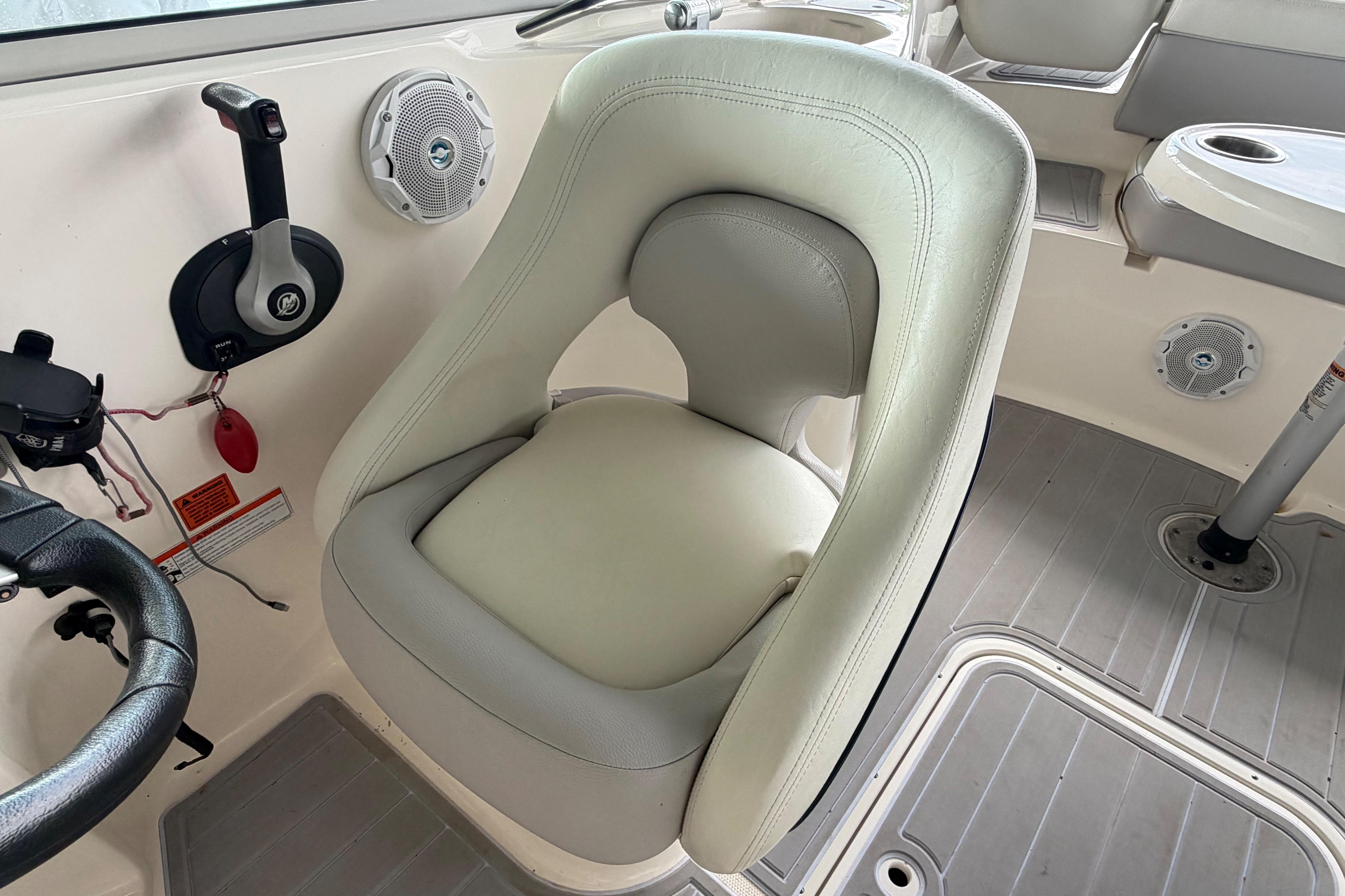 Captain's chair in a 2010 Bryant 255 boat cockpit, featuring steering wheel and controls.
