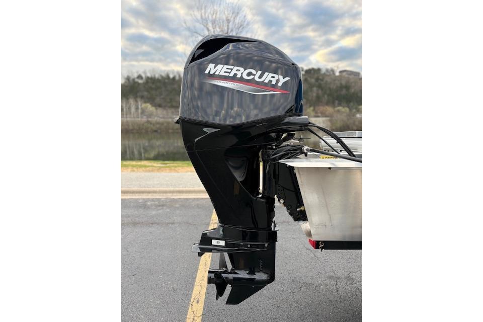 Mercury outboard motor on 2026 Sun Tracker Party Barge 16 DLX, parked near a lake.