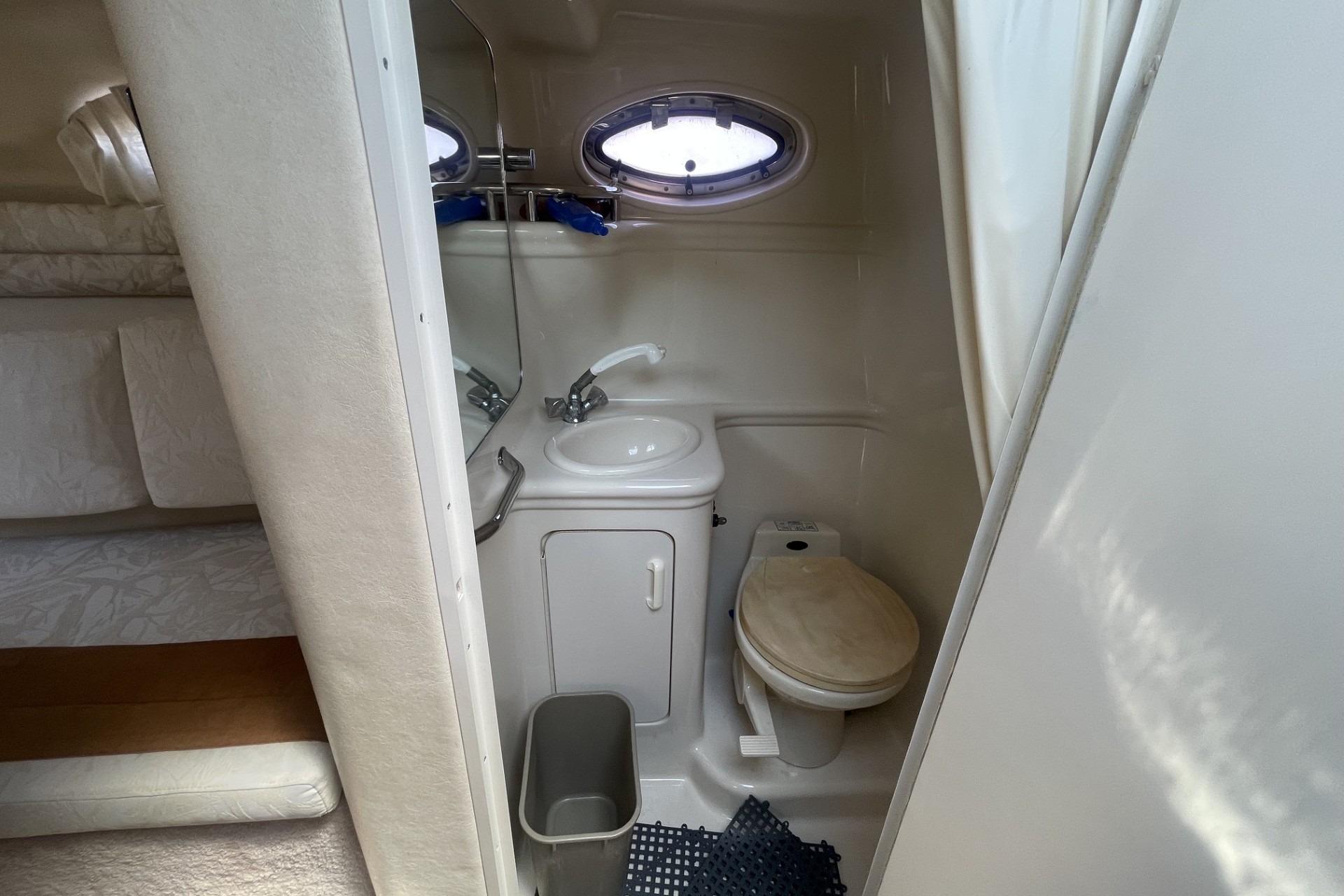 Compact bathroom in a 2000 Sea Ray Sundancer 260 boat, featuring a toilet and sink.
